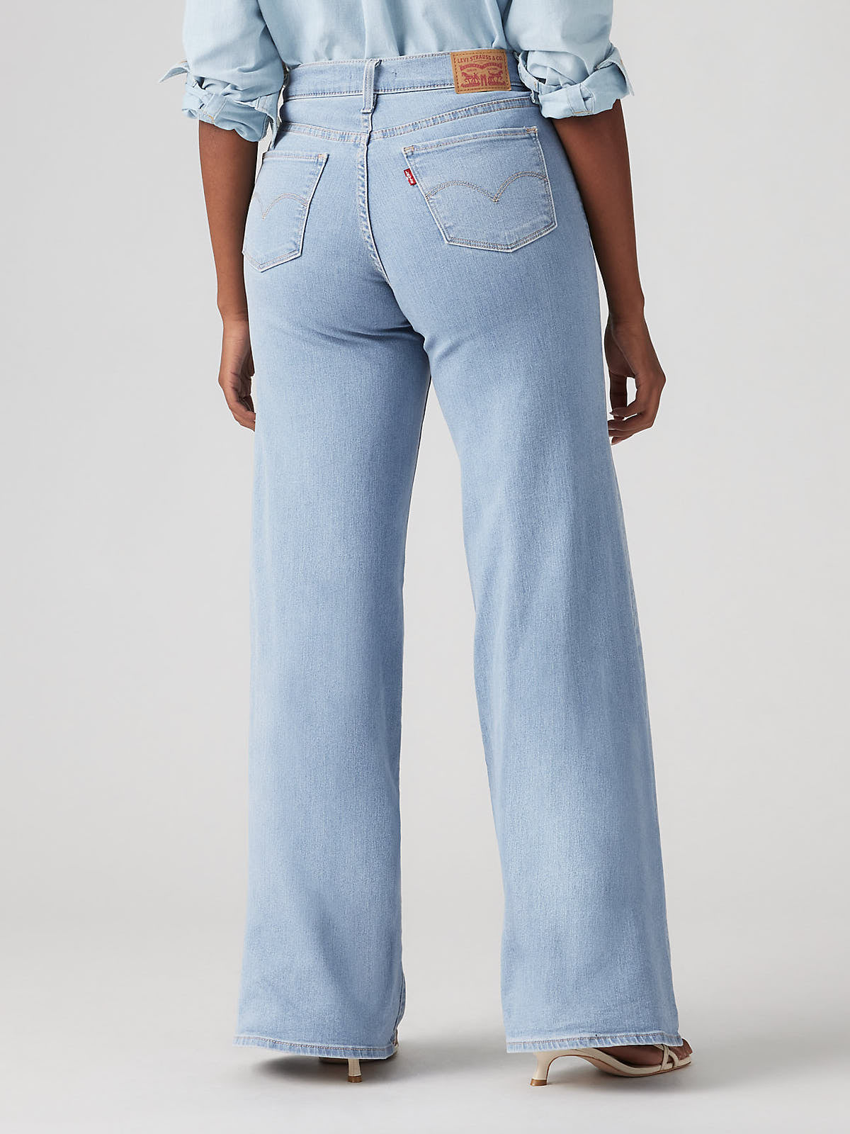 Light wash denim Levi’s 318 Shaping Tall Glass of Water Wide Jeans by Levi Strauss & Co on a model's lower body.