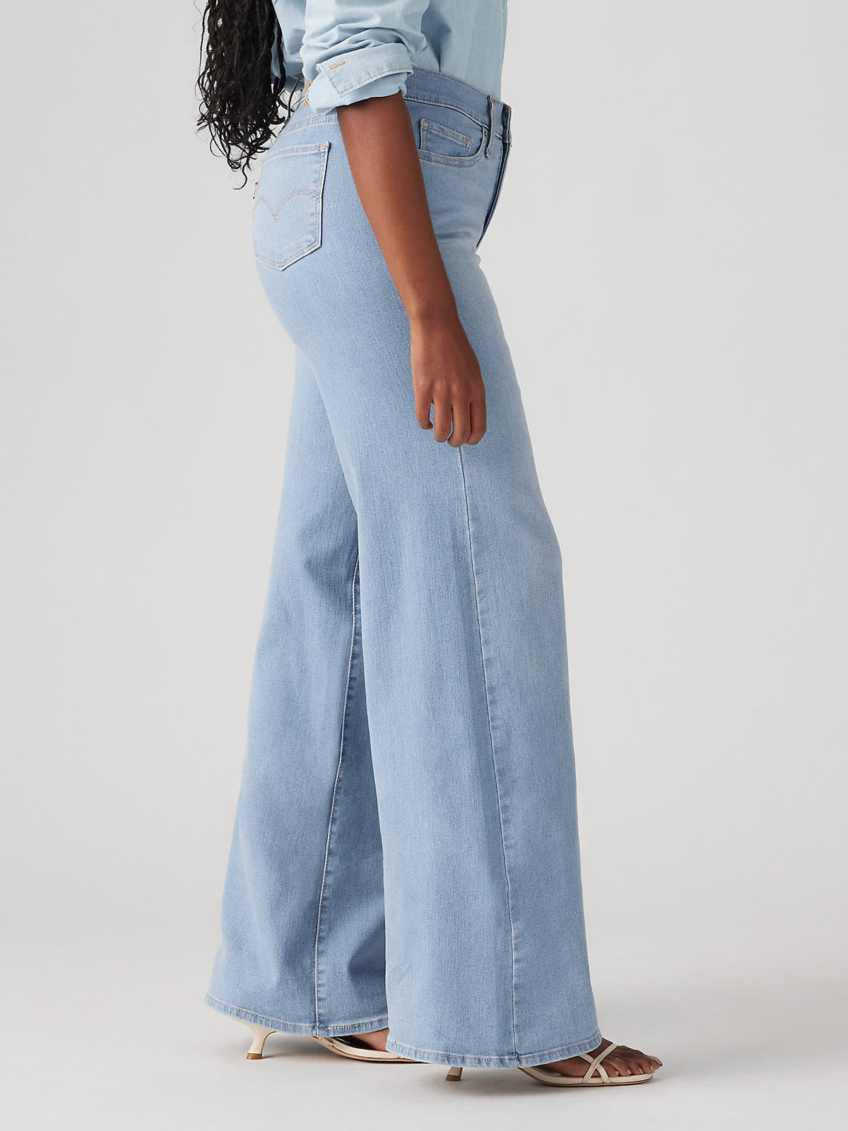 Light blue denim wide jeans styled with a light blue rolled-up sleeve shirt and sandals, Levi’s 318 Shaping Tall Glass of Water Wide Jeans by Levi Strauss & Co