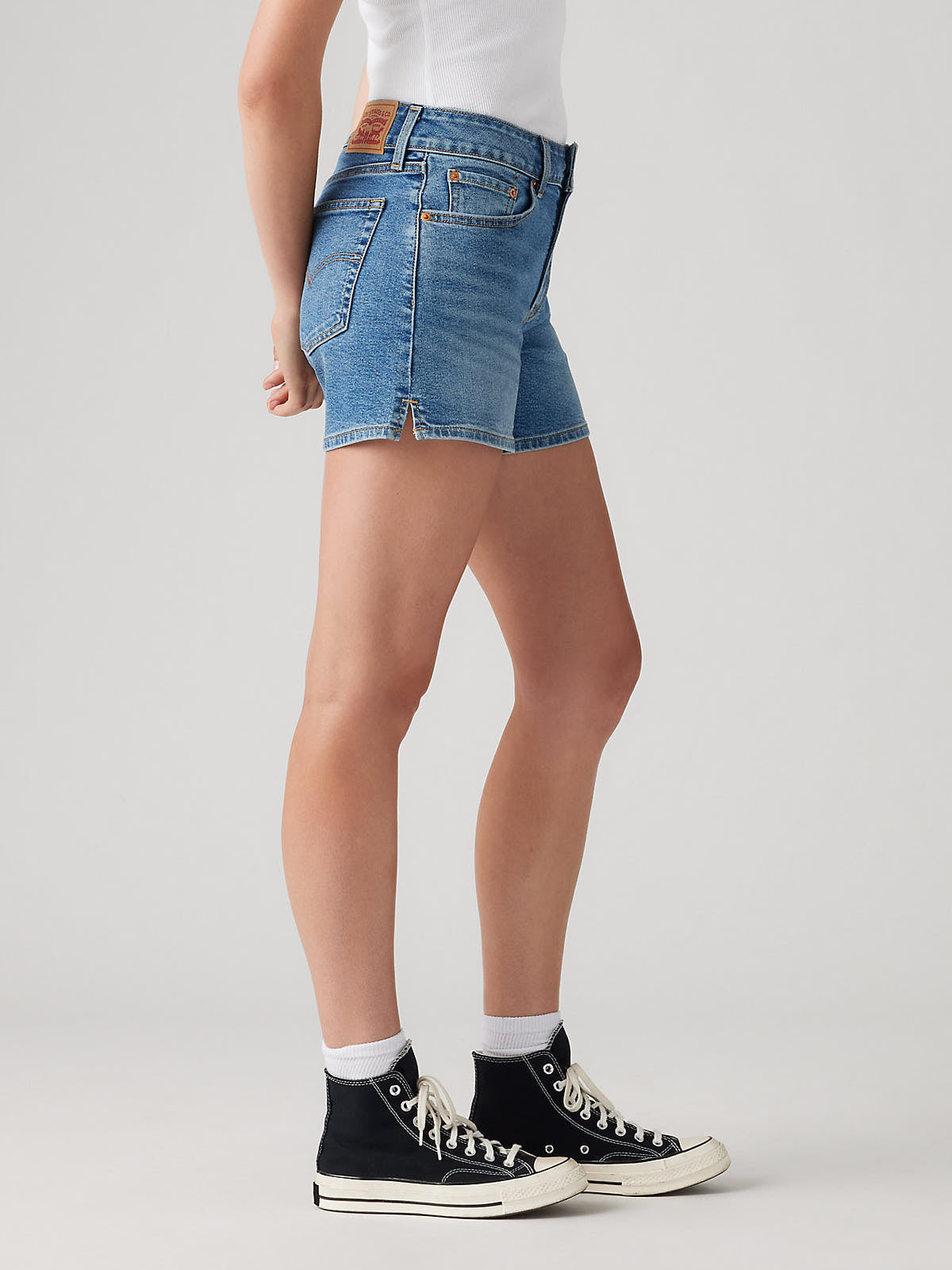Side view of Levi’s A-Line No You Didn’t Denim Short in classic blue by Levi Strauss & Co. paired with black sneakers and white socks