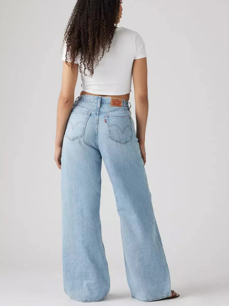 Light blue wide-leg denim jeans with a high waist and visible back pockets, paired with a white cropped top.