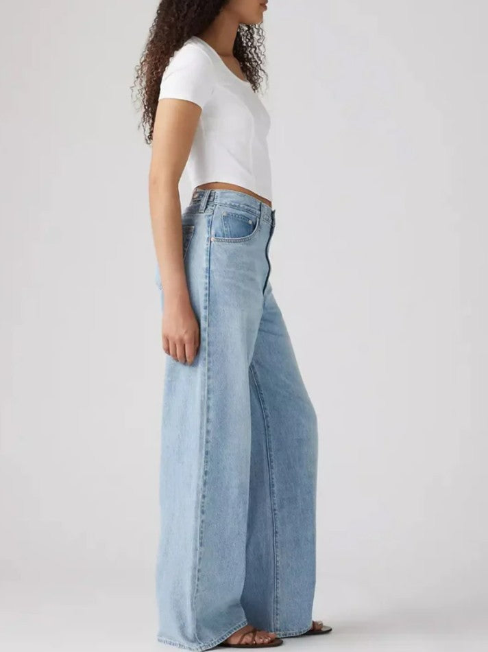 Side view of a figure wearing light blue wide-leg denim jeans and a fitted white short-sleeve top