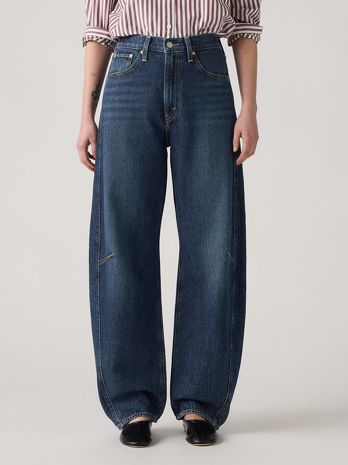 Levi’s Cinch Barrel New Shades Denim Jeans in dark blue wash styled with a striped shirt by Levi Strauss & Co.