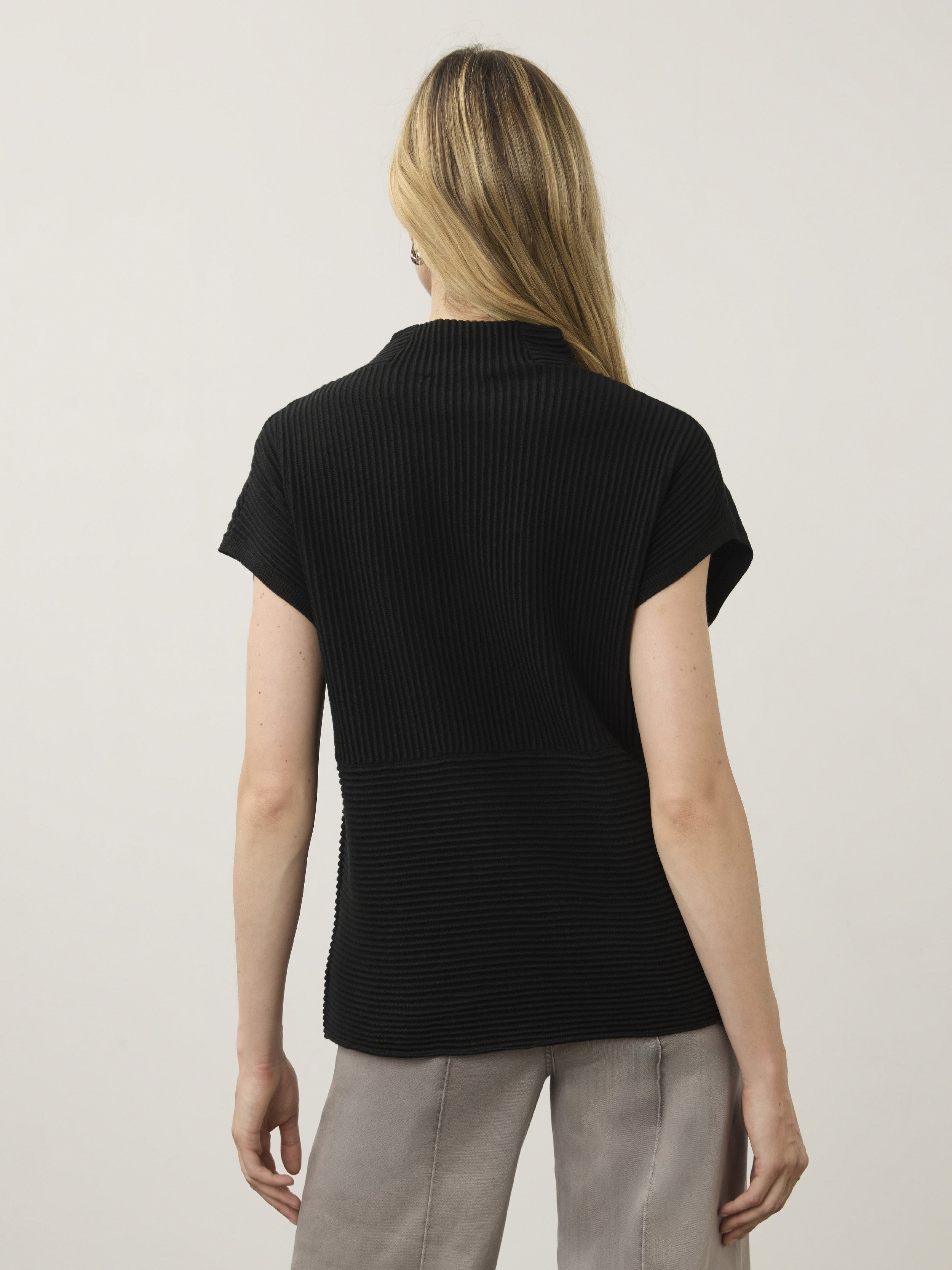 Back view of a black ribbed short-sleeve top paired with light gray pants against a plain background.