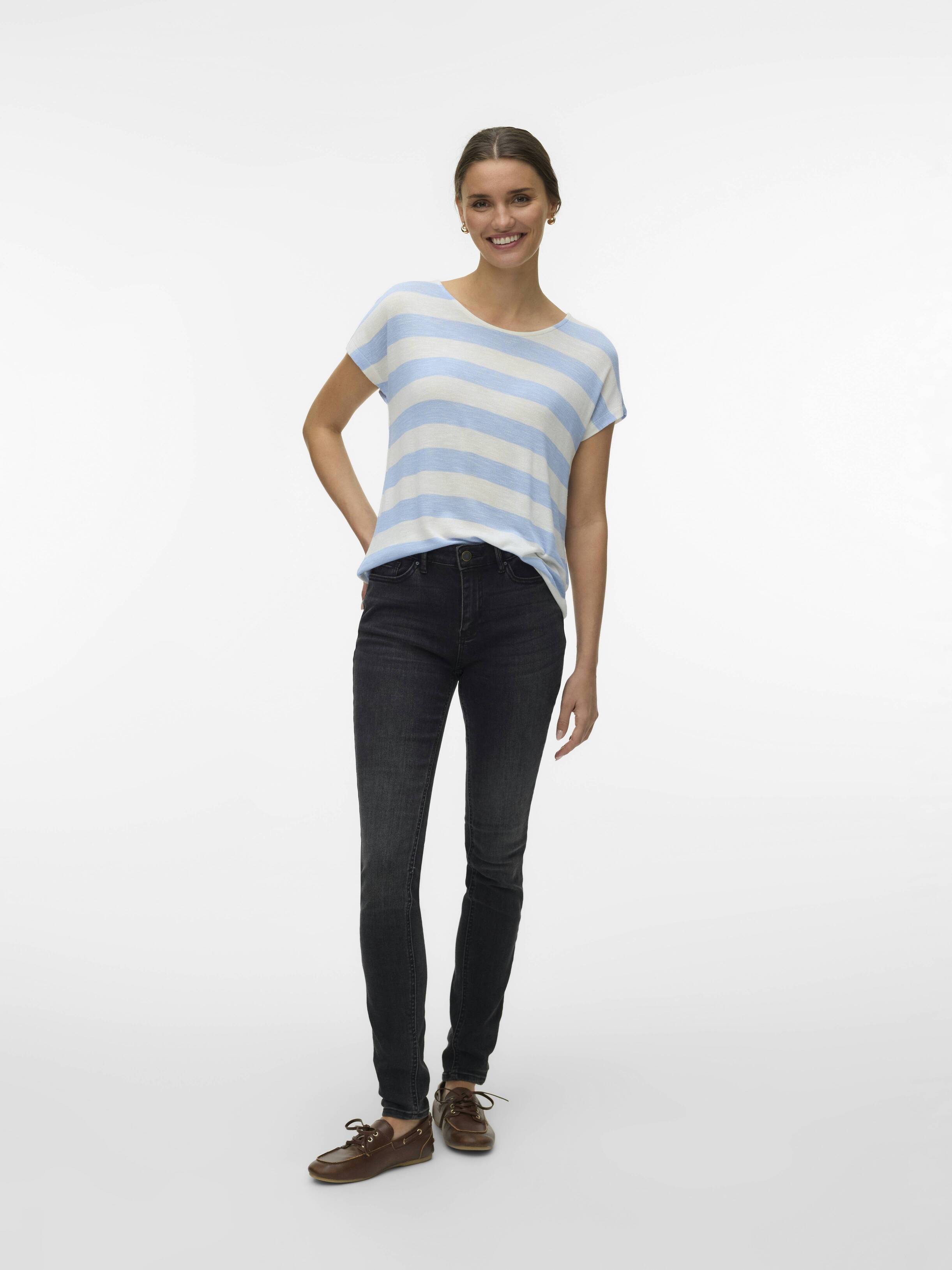 Person standing wearing light blue and white striped short-sleeve top, dark skinny jeans, and brown shoes.