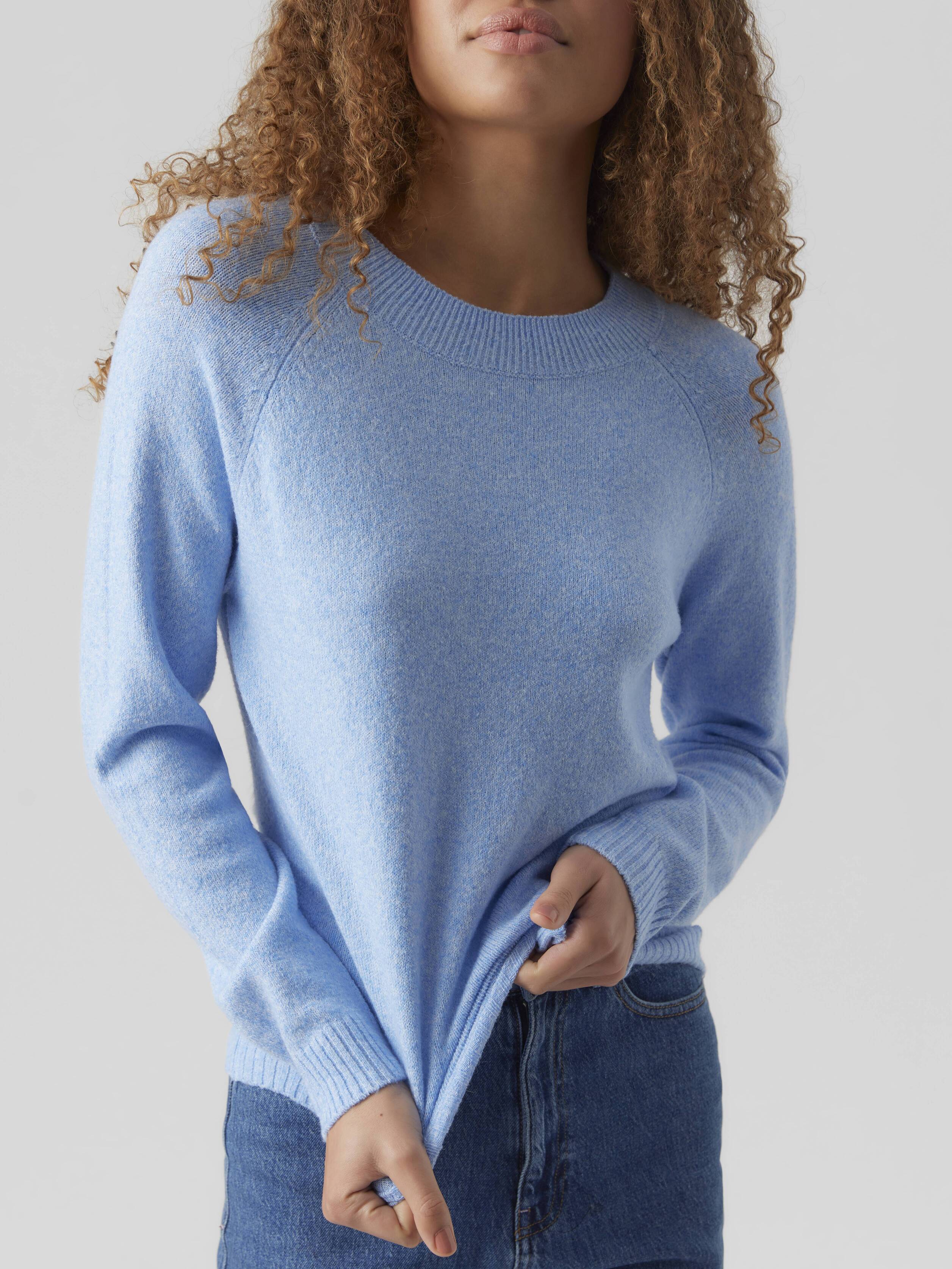 Light blue knitted sweater with long sleeves paired with blue denim jeans against a neutral background