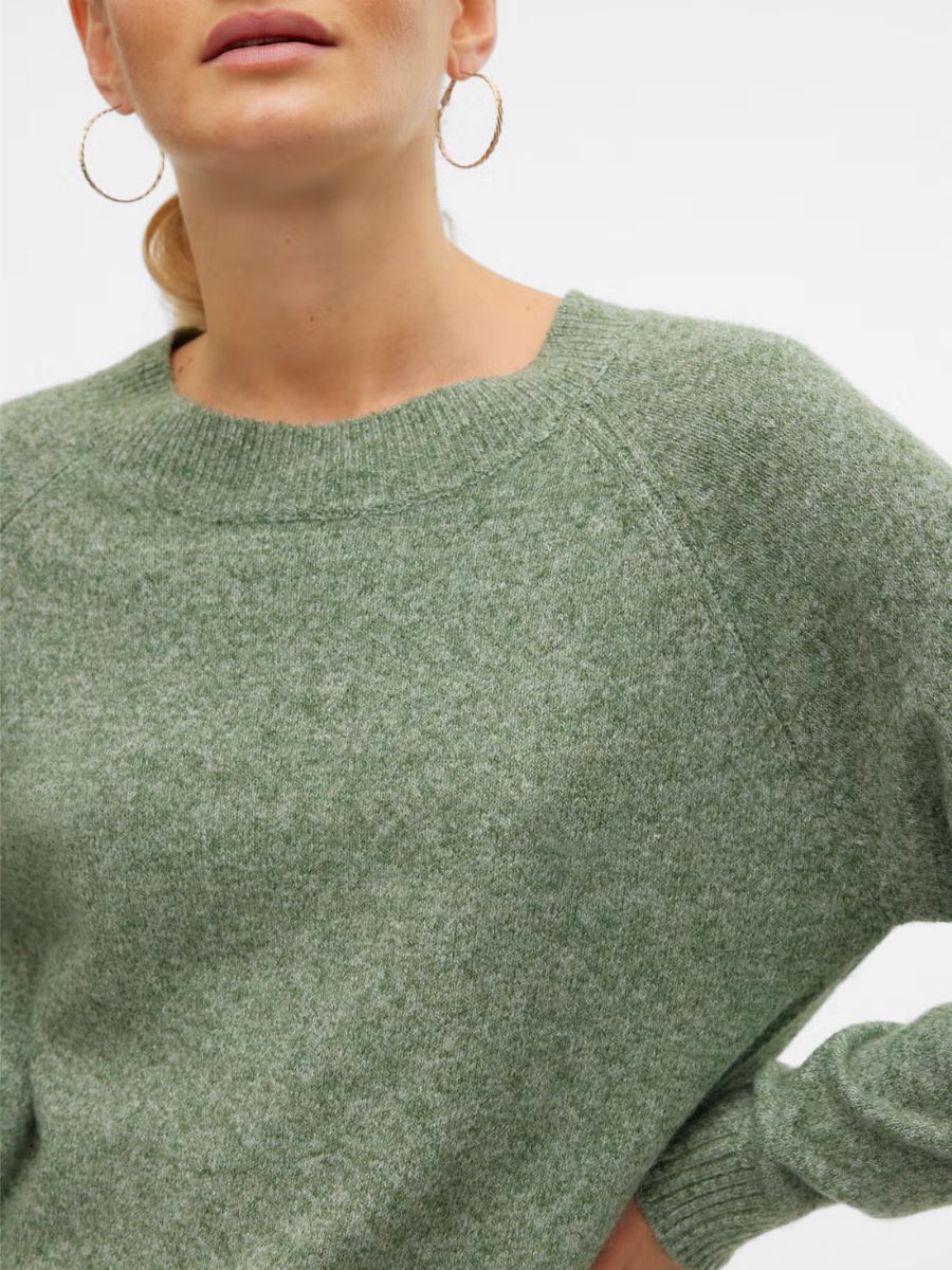 Close-up of a green textured knit sweater with ribbed crew neckline and cuffs, paired with large hoop earrings.