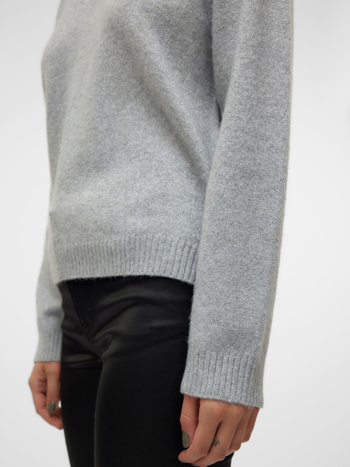 Gray knit sweater with ribbed cuffs paired with black trousers