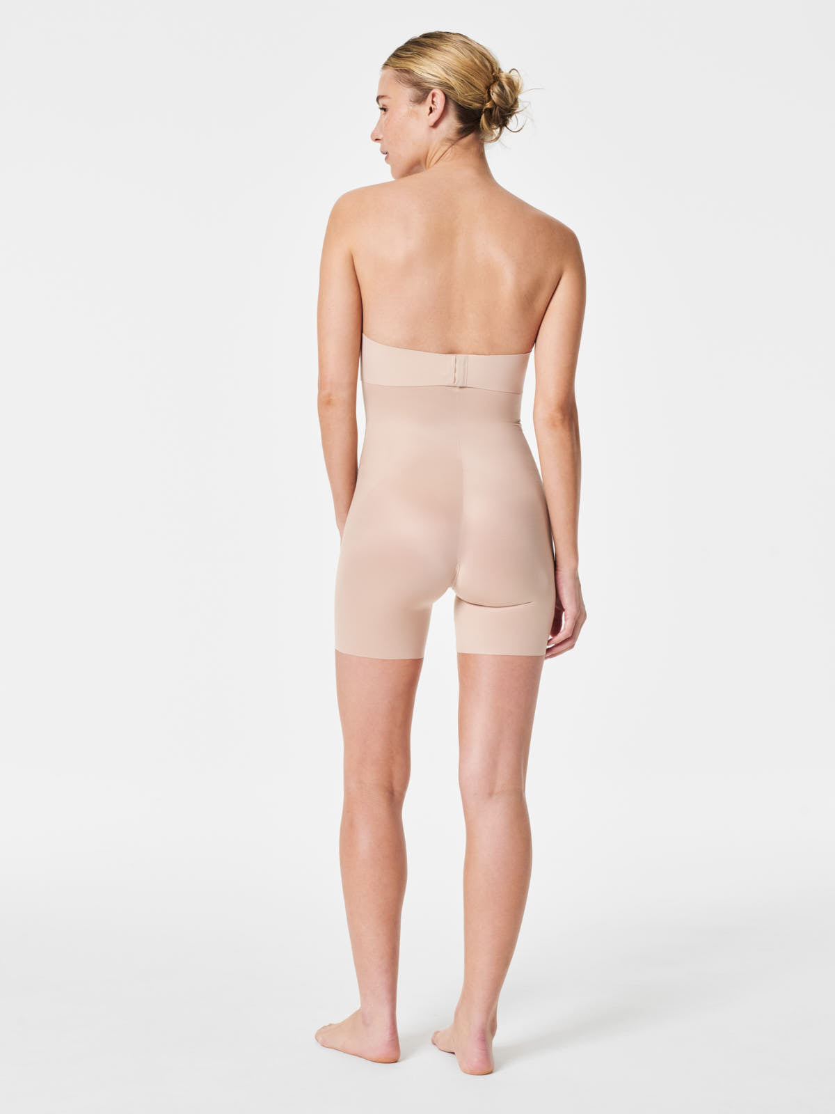 Back view of a figure wearing Spanx SPANX Thinstincts® 2.0 High-Waist Mid-Thigh Shorts in beige.