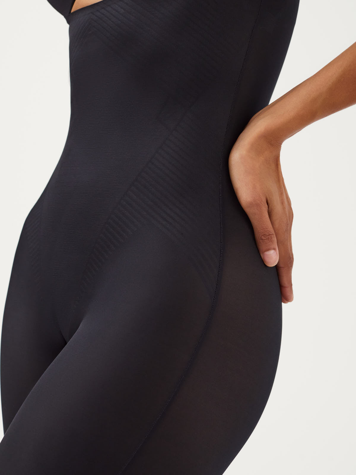 Close-up of black SPANX Thinstincts® 2.0 Mid-Thigh Bodysuit Shapewear by Spanx on torso and upper thigh