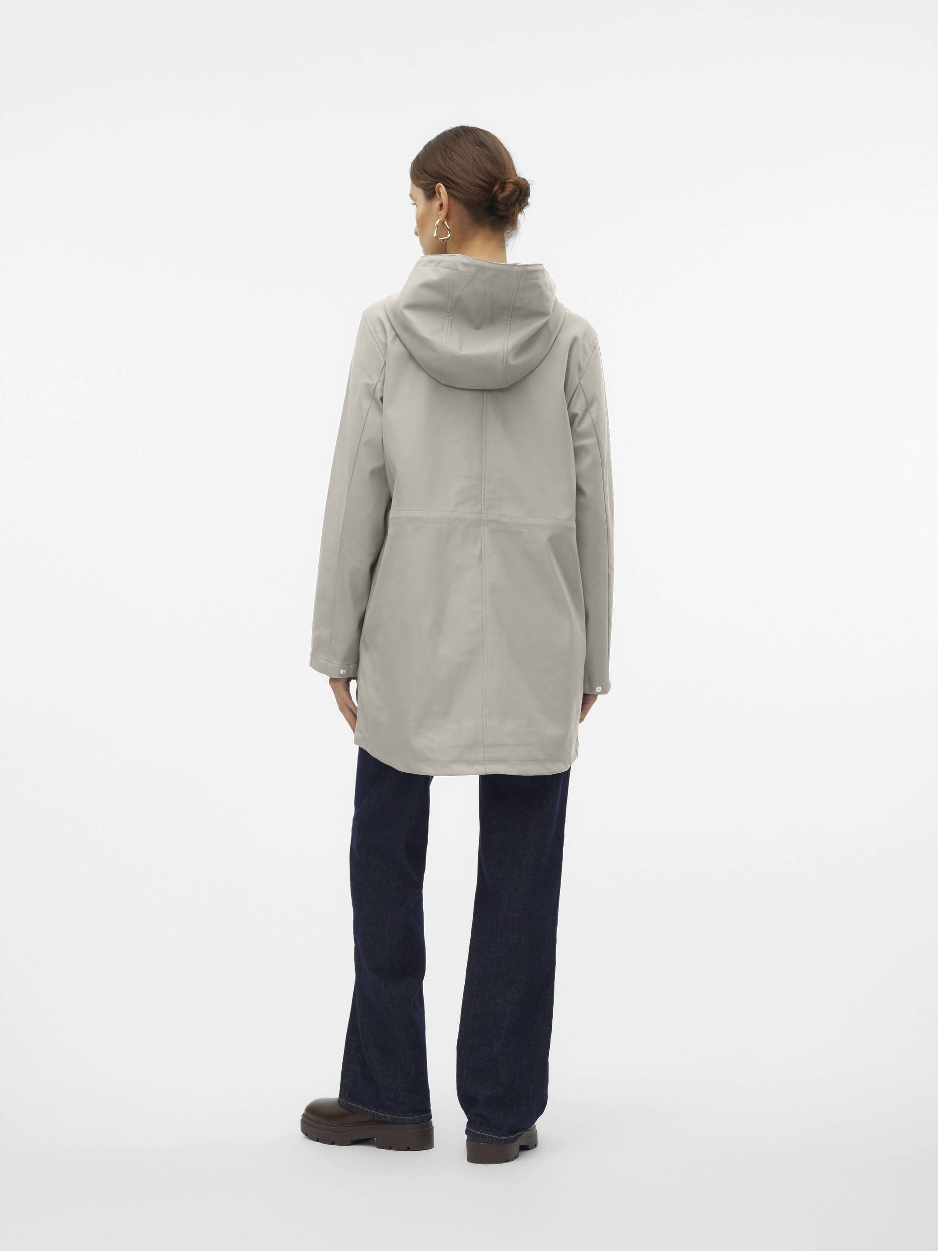 Person modeling a light beige hooded coat paired with dark blue pants and brown shoes, shown from the back.