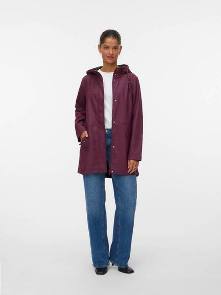 Person wearing a wine-colored hooded raincoat over a white top and blue jeans against a plain background