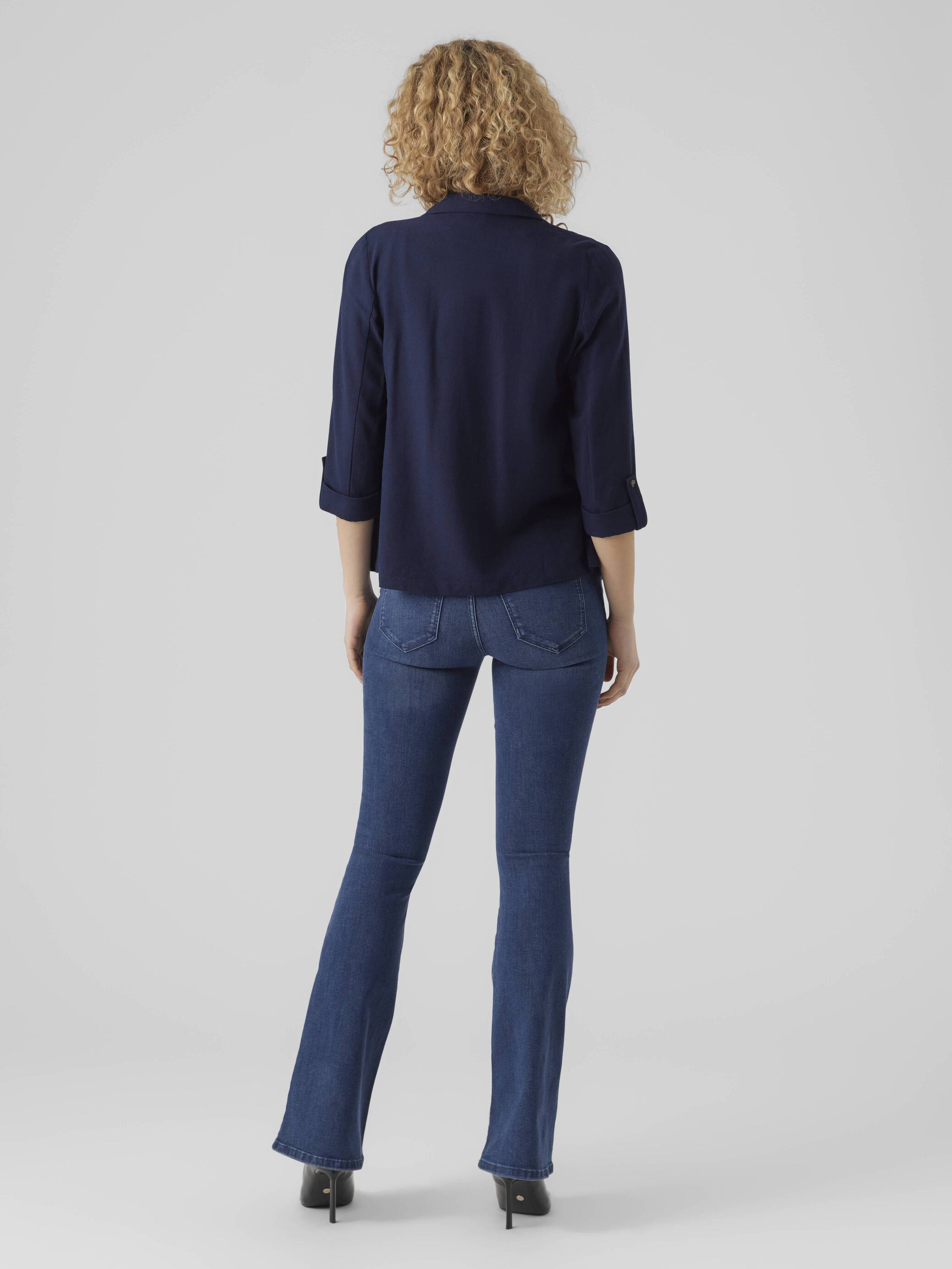 Back view of a navy blouse paired with jeans and heels featuring the Vero Moda Jensen Blazer branding.