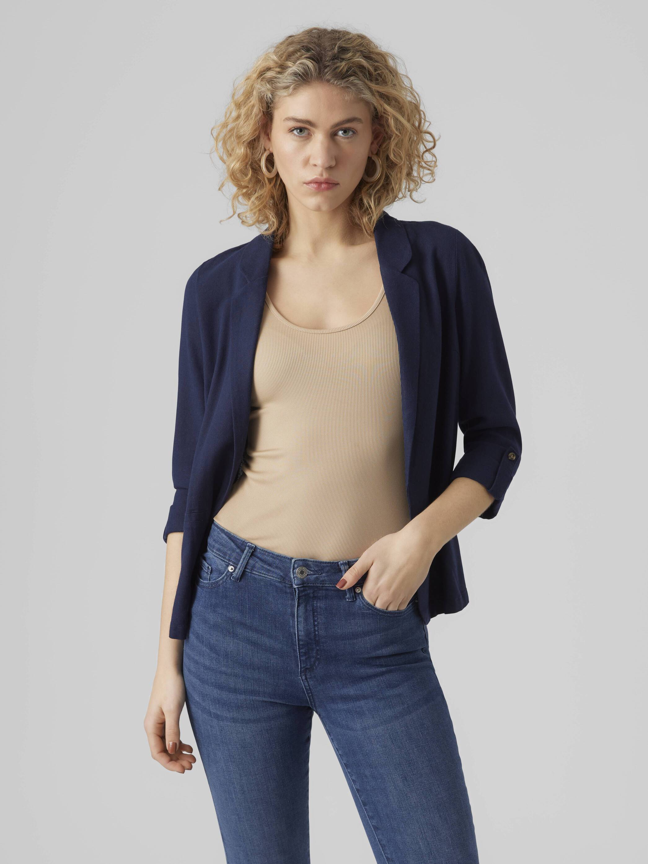 Vero Moda Jensen Blazer in navy blue, styled over a beige top with rolled-up sleeves, paired with blue jeans.