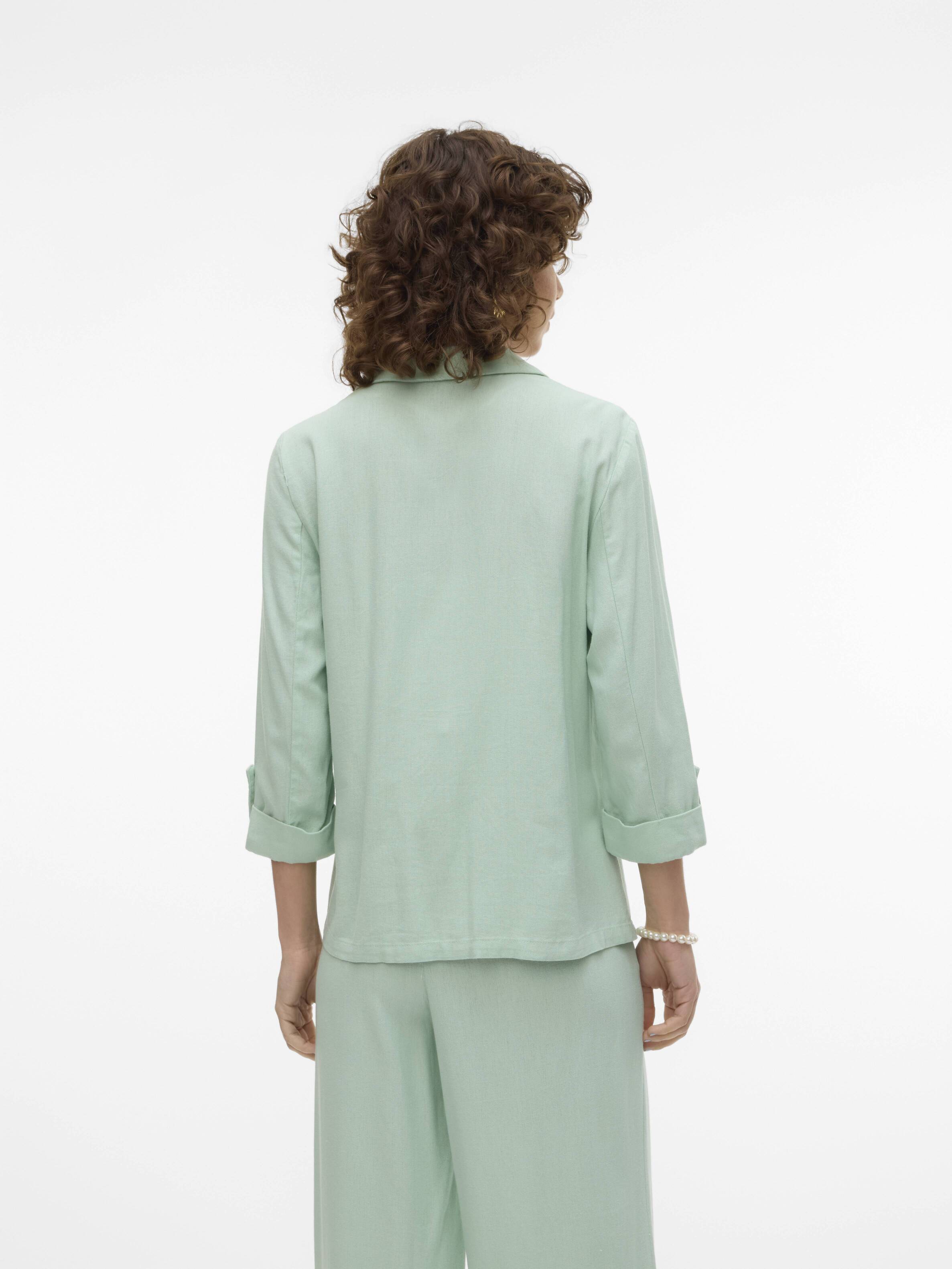 Vero Moda Jensen Blazer in soft sage green, featuring rolled-up sleeves and a relaxed fit outerwear design.