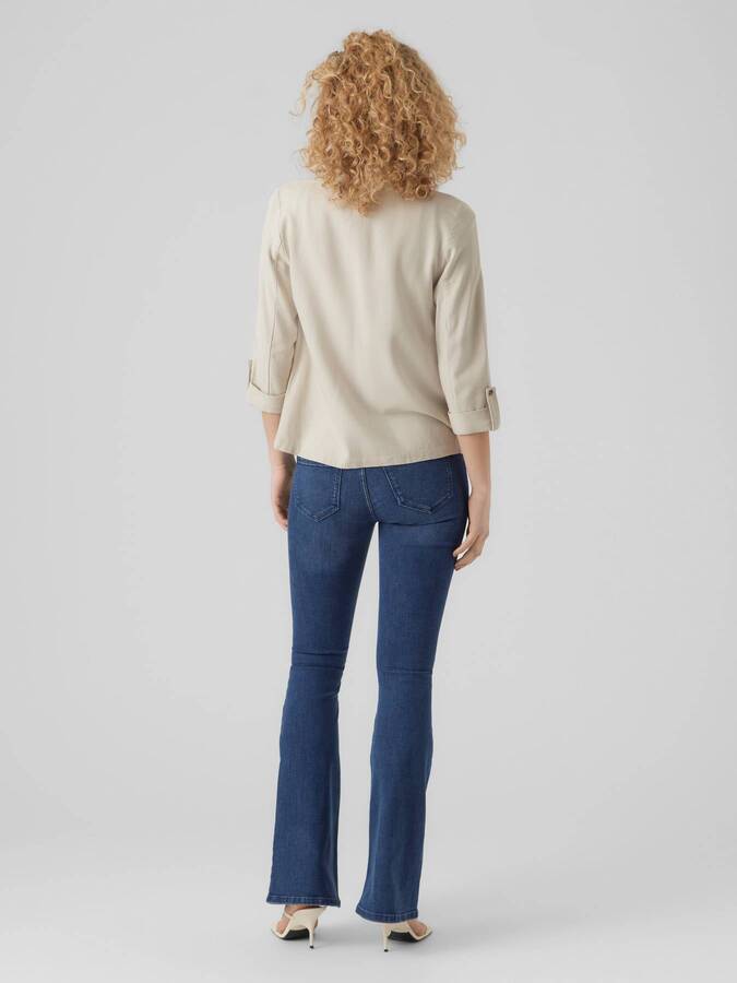 Back view of light beige Vero Moda Jensen Blazer paired with blue denim jeans and white heels on gray background