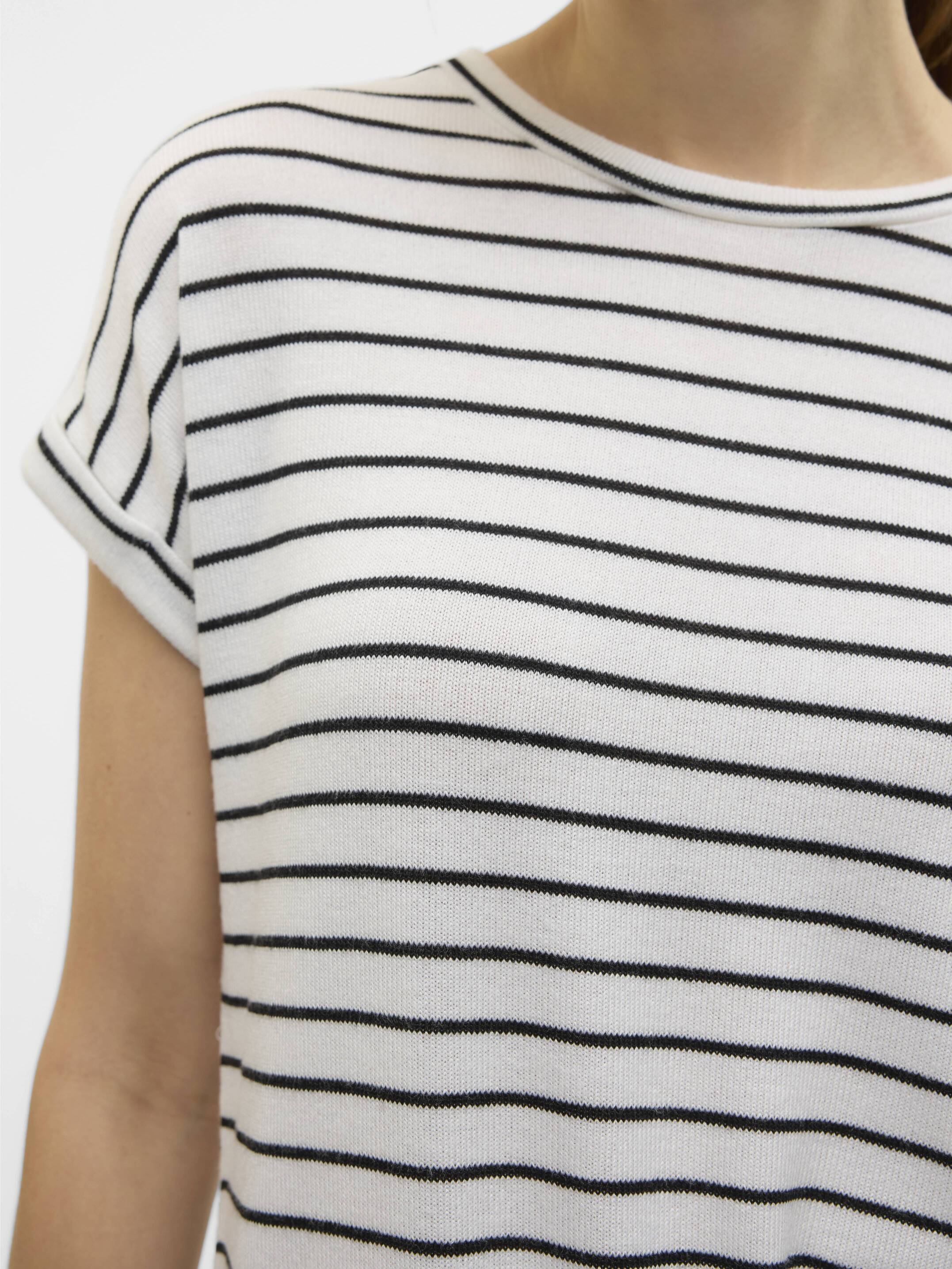 Close-up of a white knit top with thin black horizontal stripes and rolled short sleeves on a person