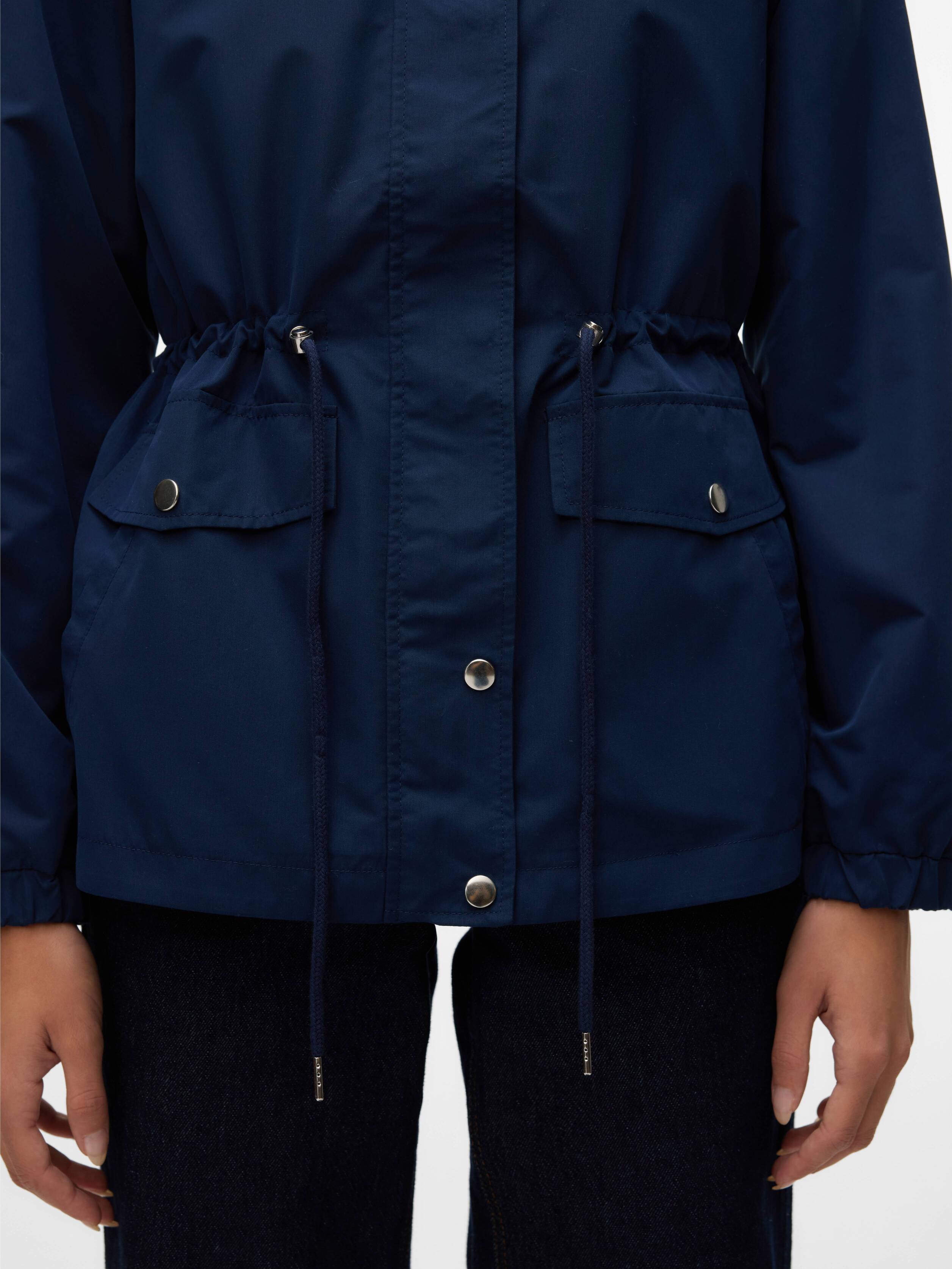 Navy blue jacket with front snap buttons, drawstring waist, and flap pockets paired with dark denim pants.