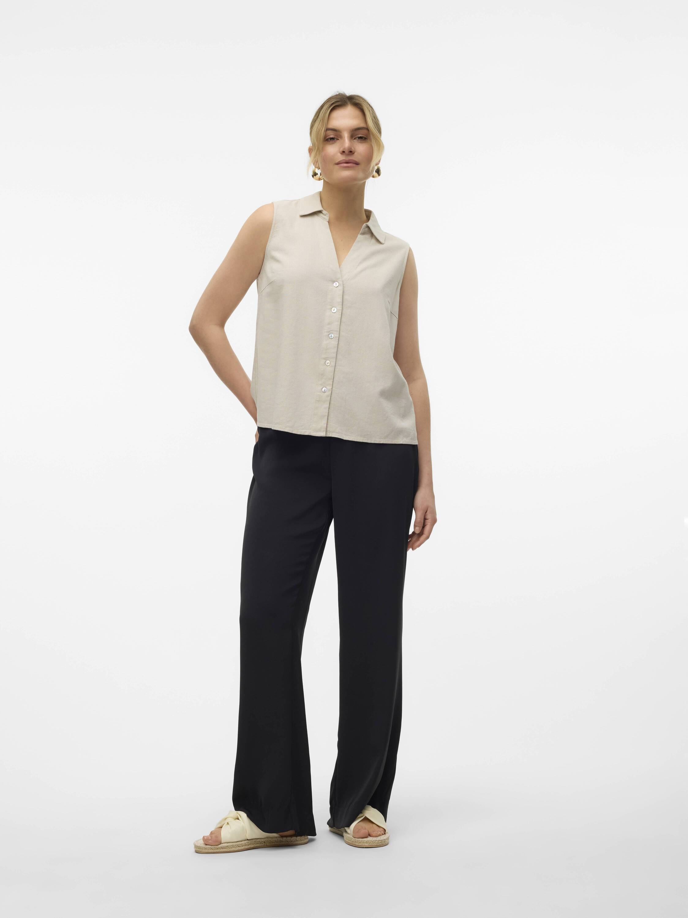 Model in beige Vero Moda My Nen Sleeveless V-Neck Top paired with black pants and sandals against white background