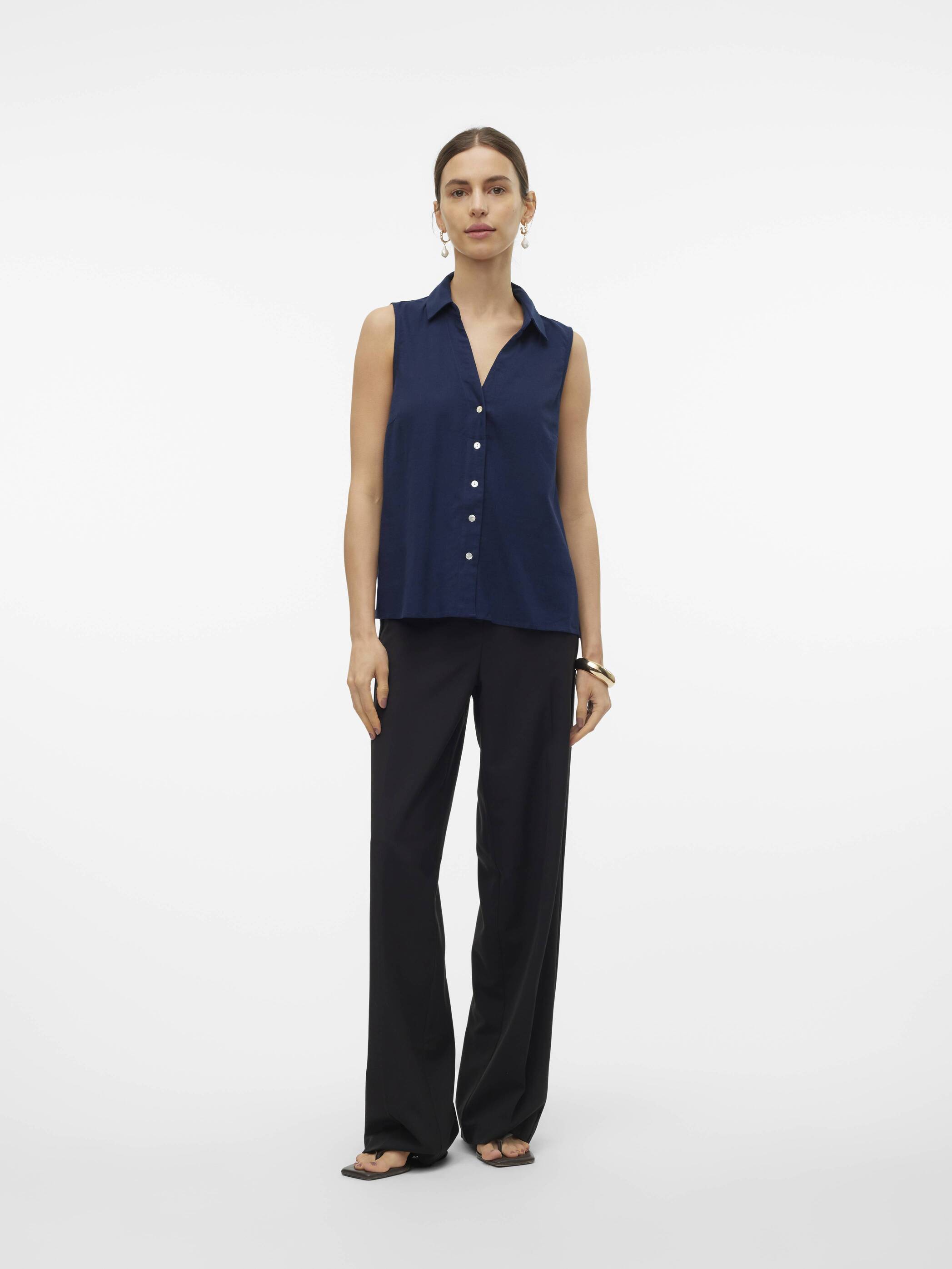 Vero Moda My Nen Sleeveless V-Neck Top in navy, featuring button front and collar, styled with black trousers.
