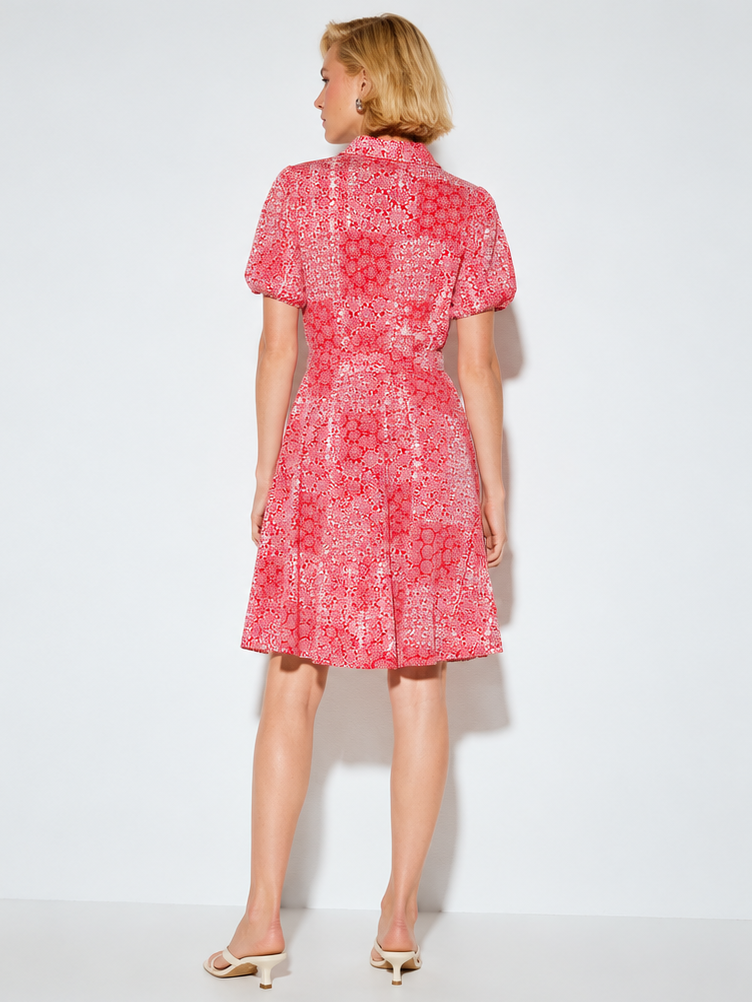 Back view of a knee-length red patterned dress with short sleeves and a fitted waist paired with beige heeled sandals.