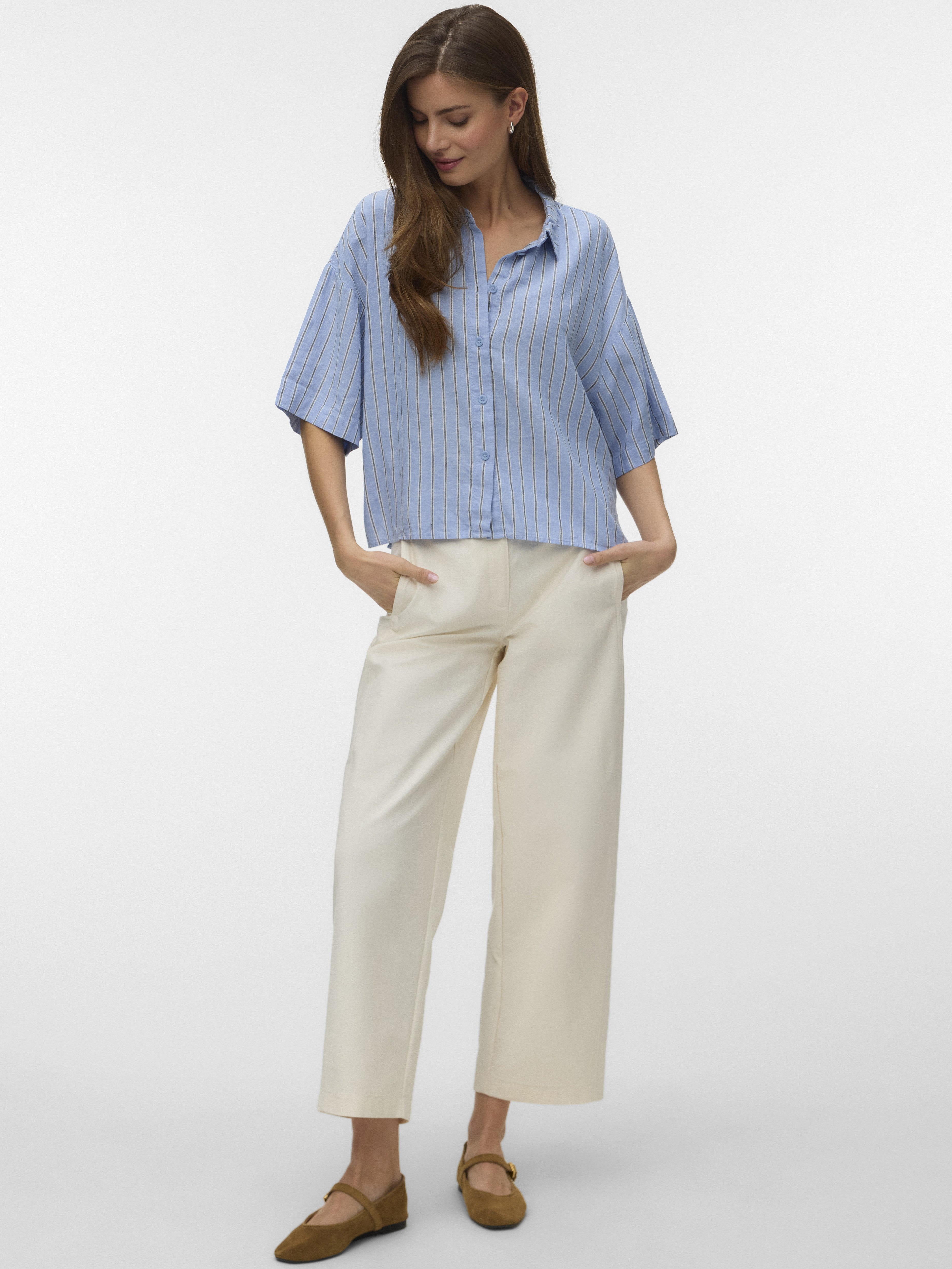 Light blue striped short-sleeve button-up shirt paired with cream wide-leg pants and brown flat shoes.