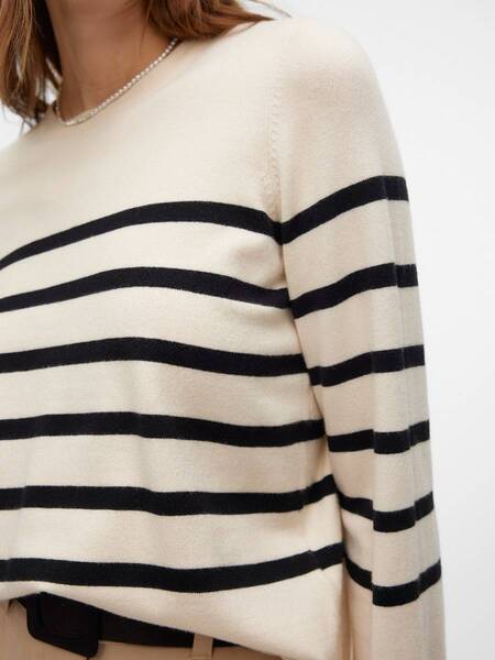 Close-up of a beige sweater with black horizontal stripes on the sleeves and torso, paired with beige pants.