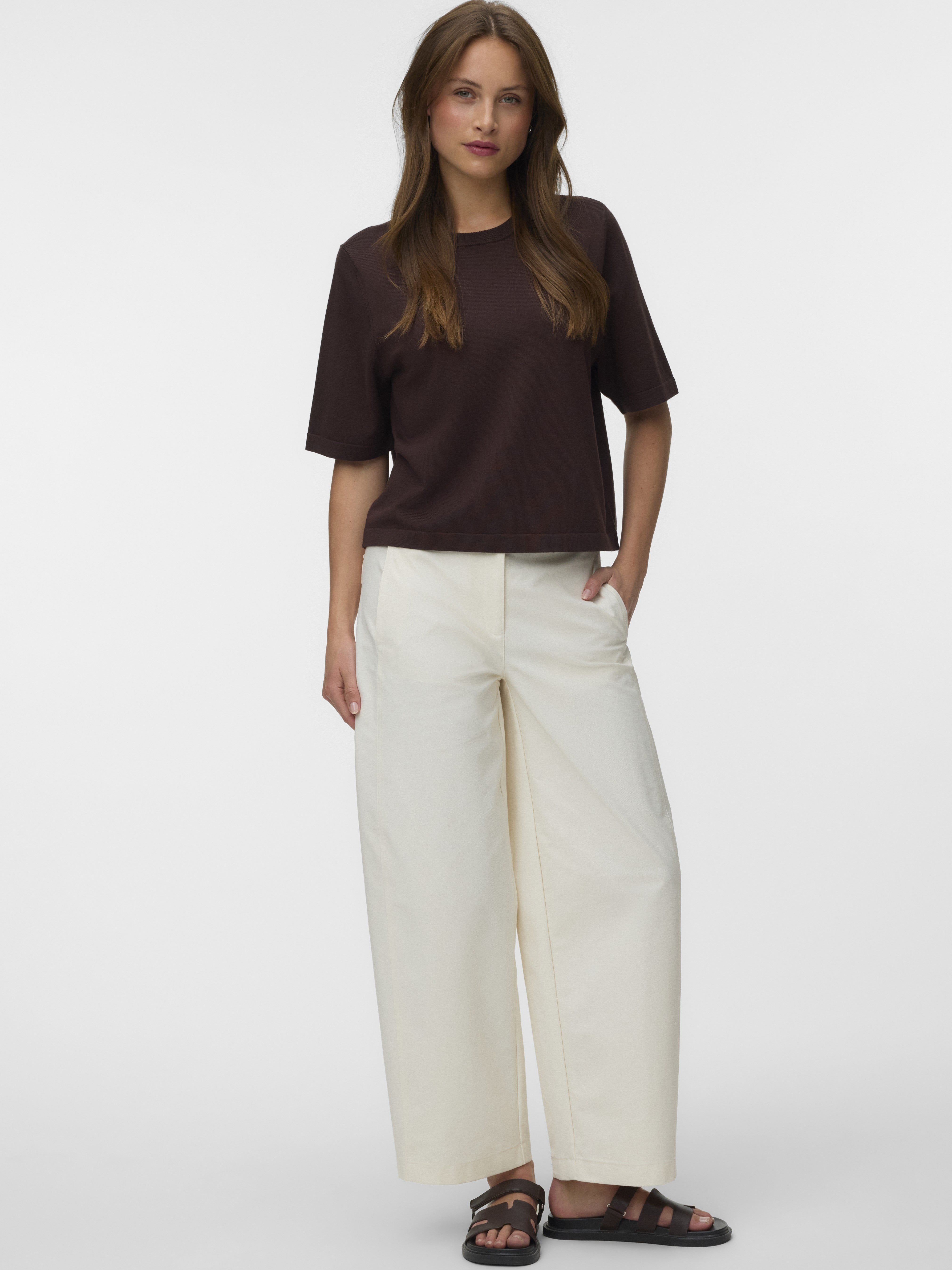 Casual outfit featuring a dark brown short-sleeve top paired with wide-leg off-white pants and black sandals.