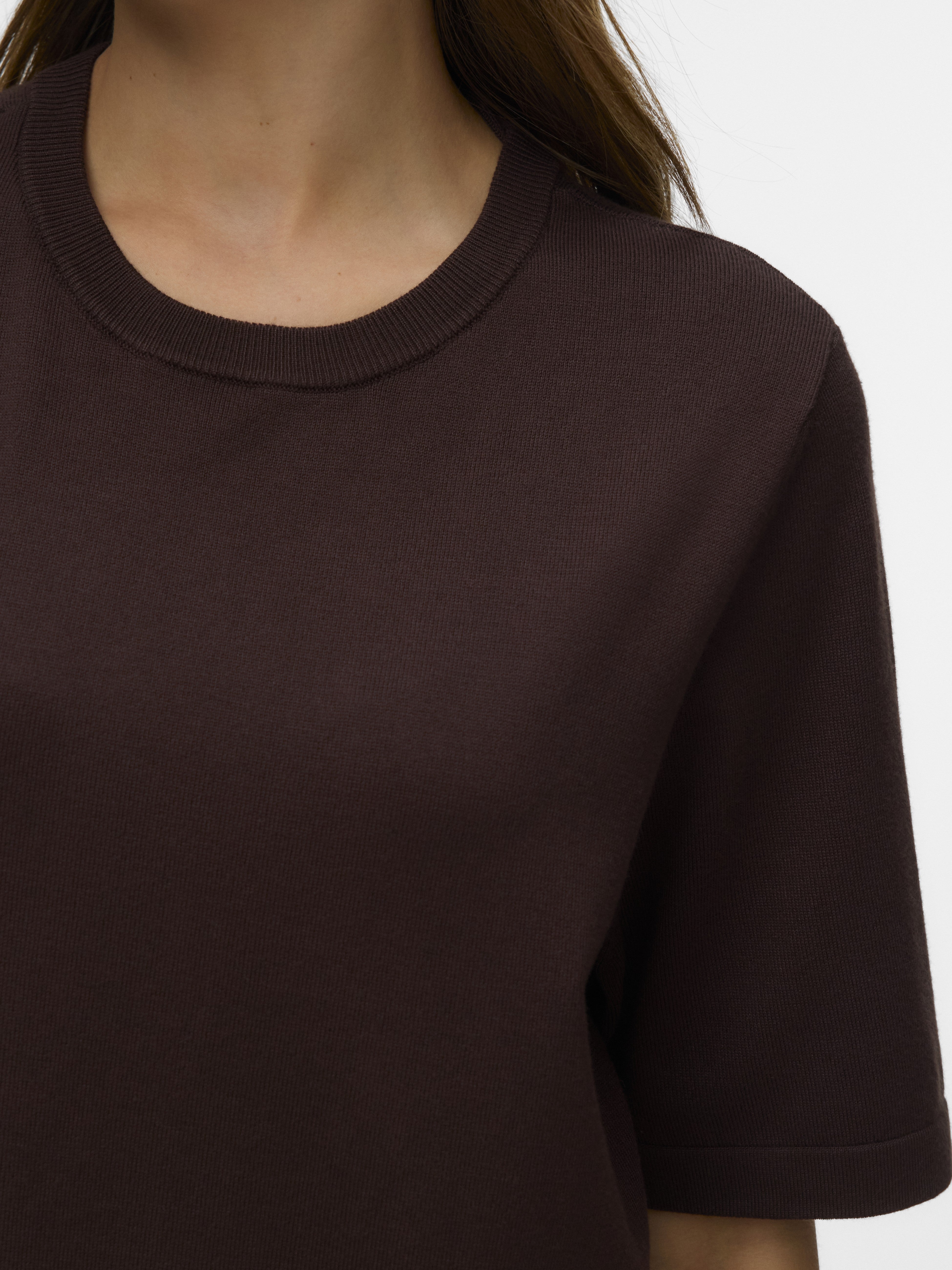 Close-up of a chocolate brown knitted short-sleeve sweater with a round neckline.