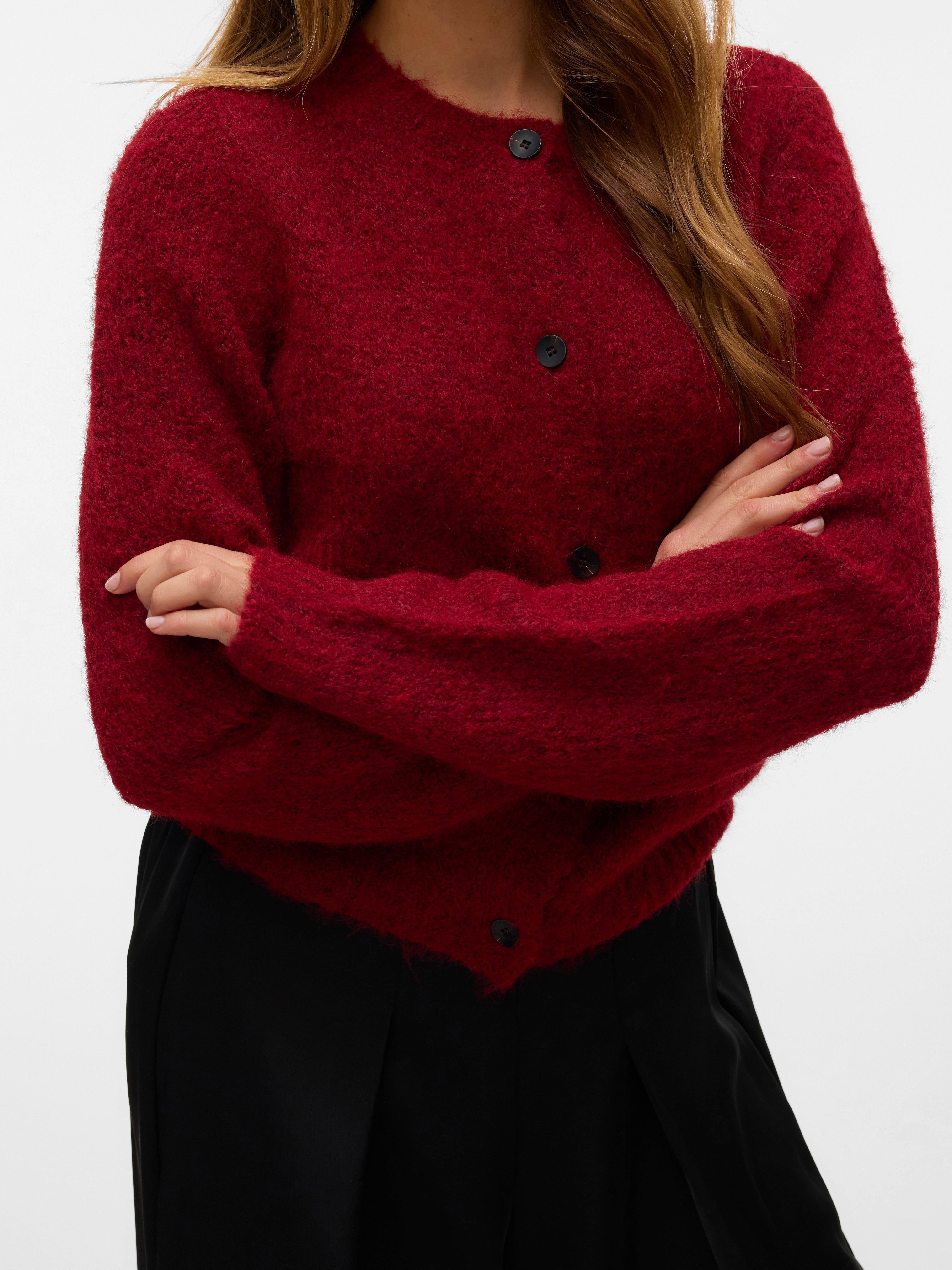 Red textured button-up sweater paired with black high-waisted pants against a plain background.