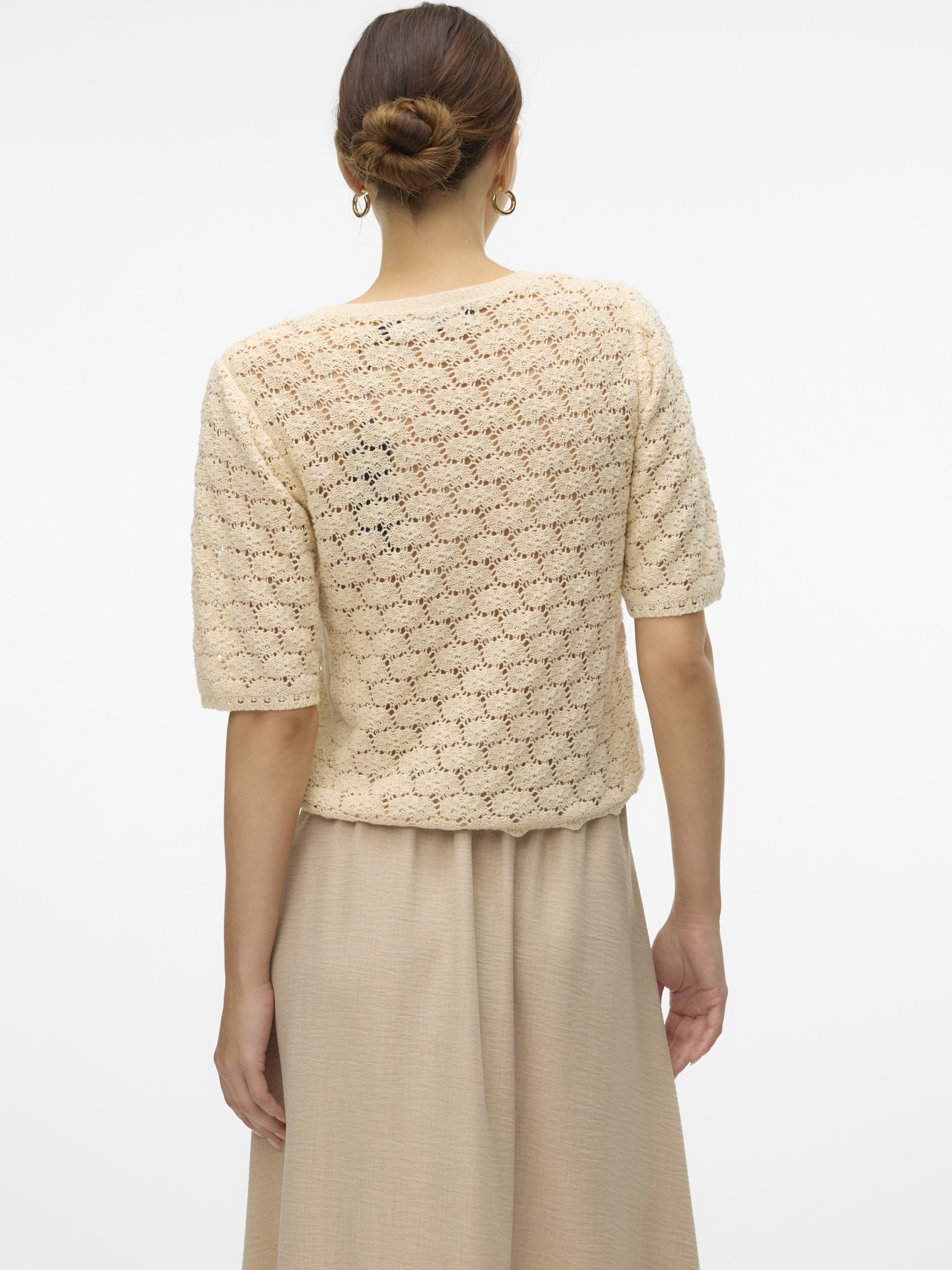 Vero Moda Kora Crochet Short Sleeve Cardigan in off-white crochet knit, styled with neutral skirt, showcasing outerwear texture.