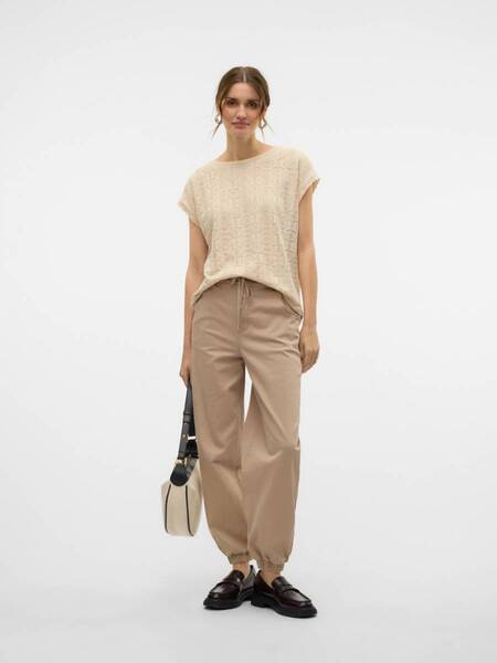 Beige short-sleeve textured top paired with tan drawstring wide-leg pants and dark loafers, holding a two-tone bag.