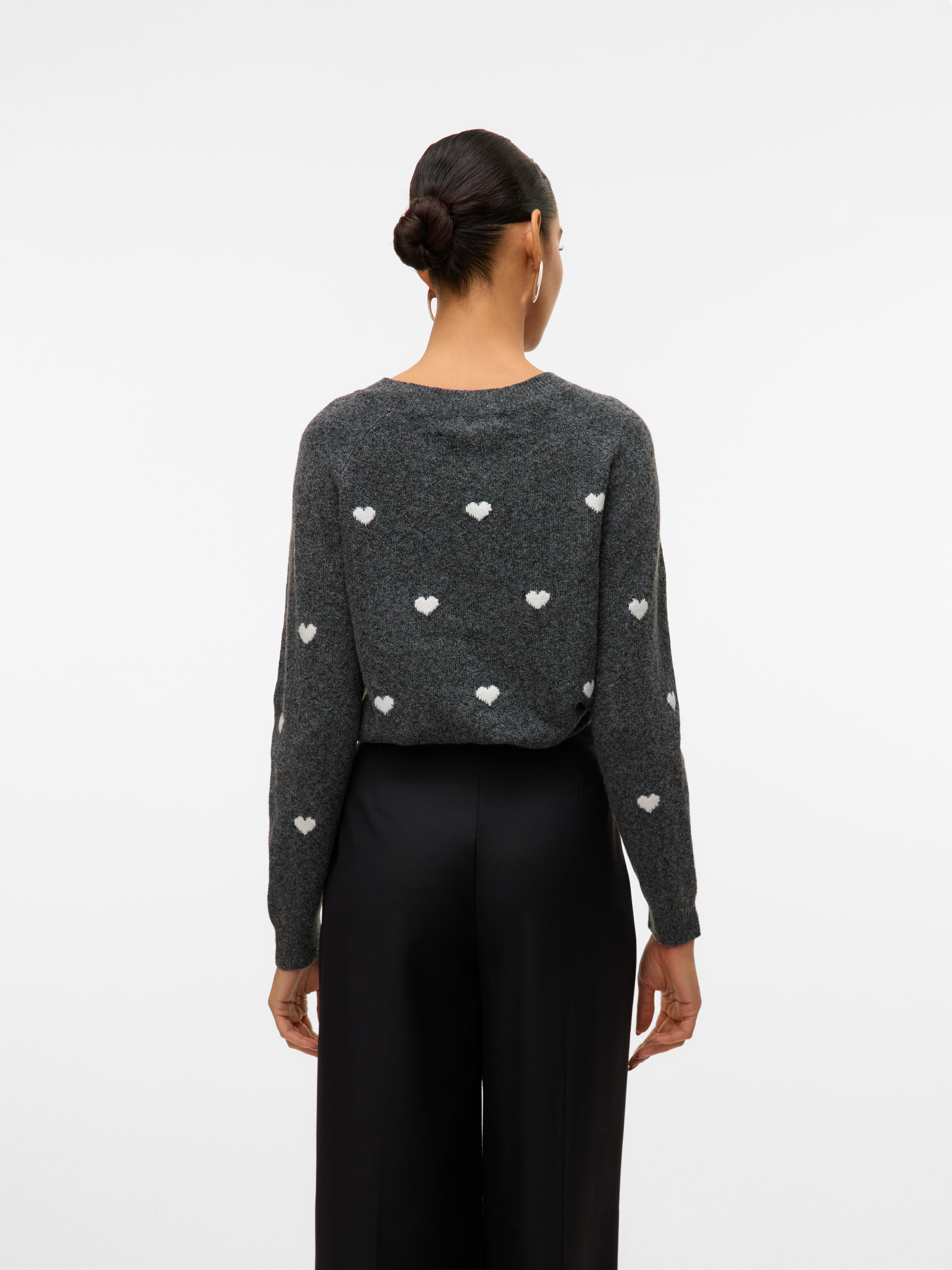 Dark gray sweater with white heart patterns paired with loose black trousers viewed from the back