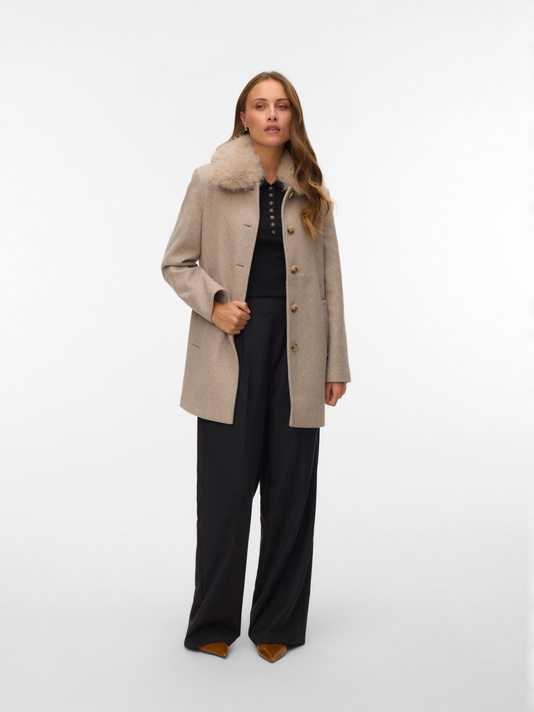 Full-length view of a beige coat with a fur collar over a black outfit