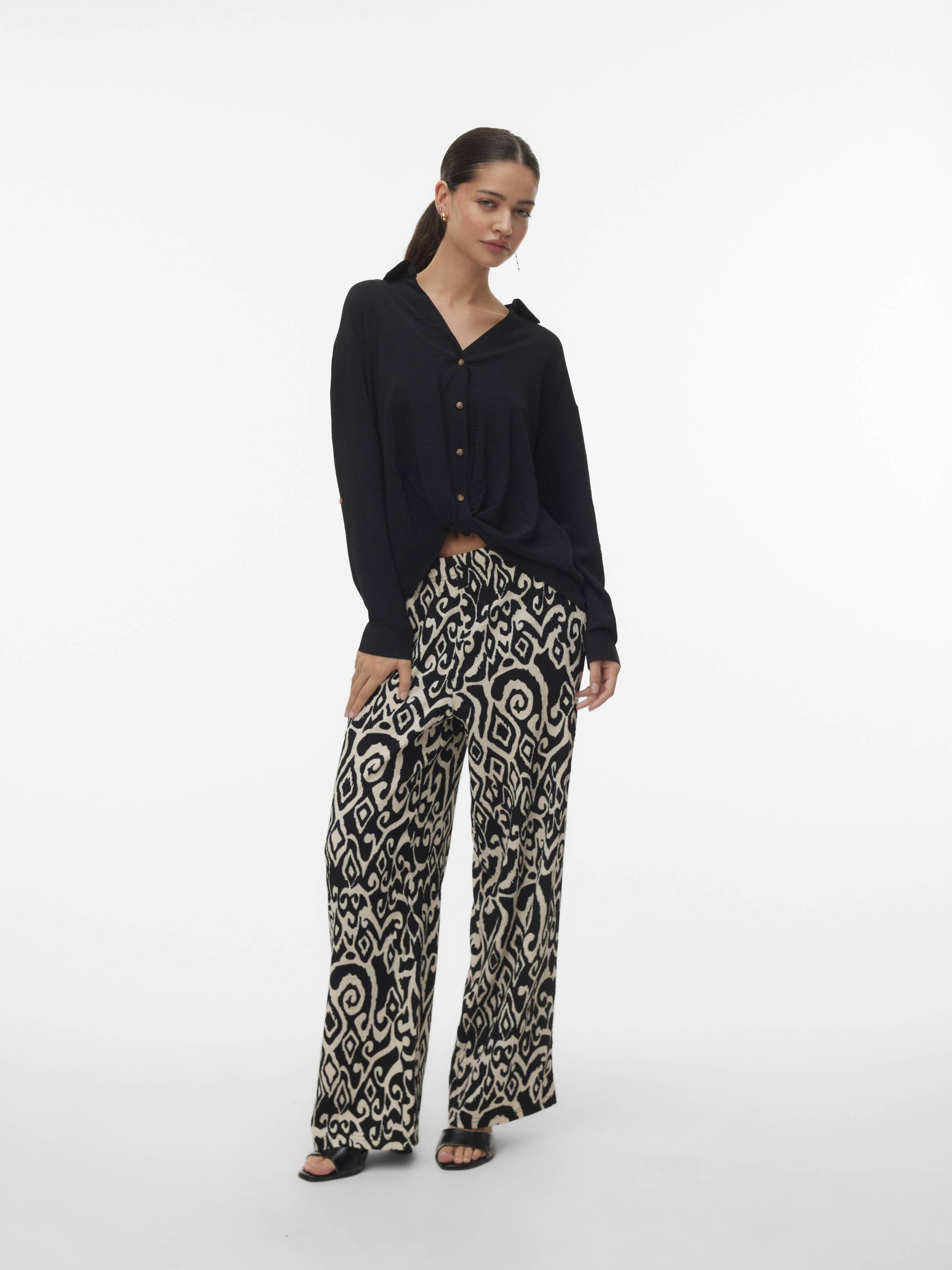 Black button-up long sleeve top paired with high-waisted beige and black patterned wide-leg pants