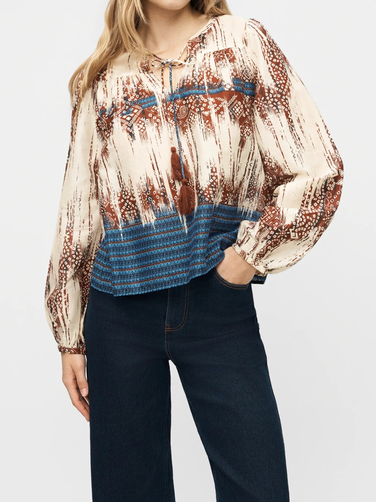 Vero Moda Eliza Border Print Long Sleeve Top in beige with rust and blue patterns, paired with dark denim jeans.