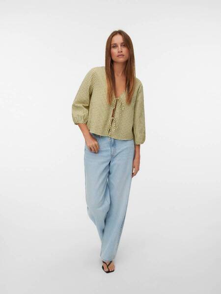 Model in light green top and light blue jeans on white background, featuring Vero Moda Came Fitted Sleeveless Top by Vero Moda