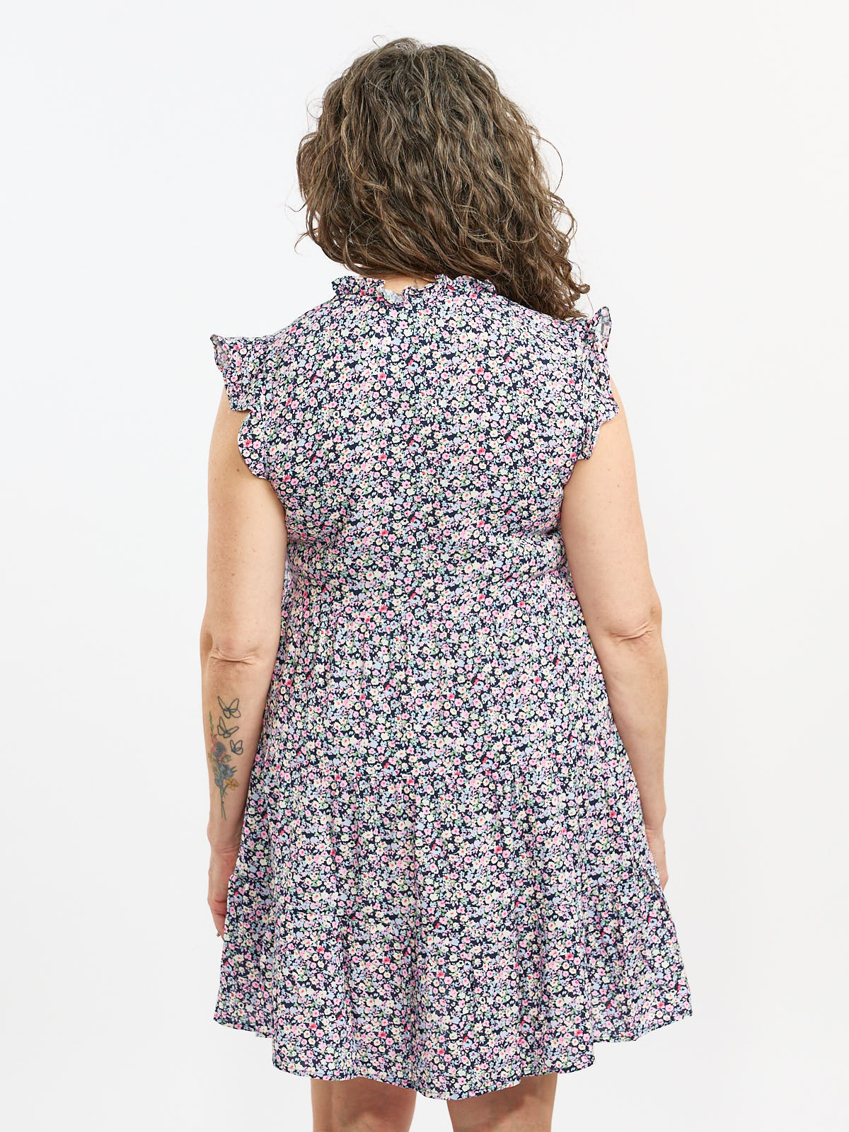 Back view of Vero Moda Alba Disty Tie-Neck Short Sleeve Dress featuring floral pattern and ruffled shoulders.