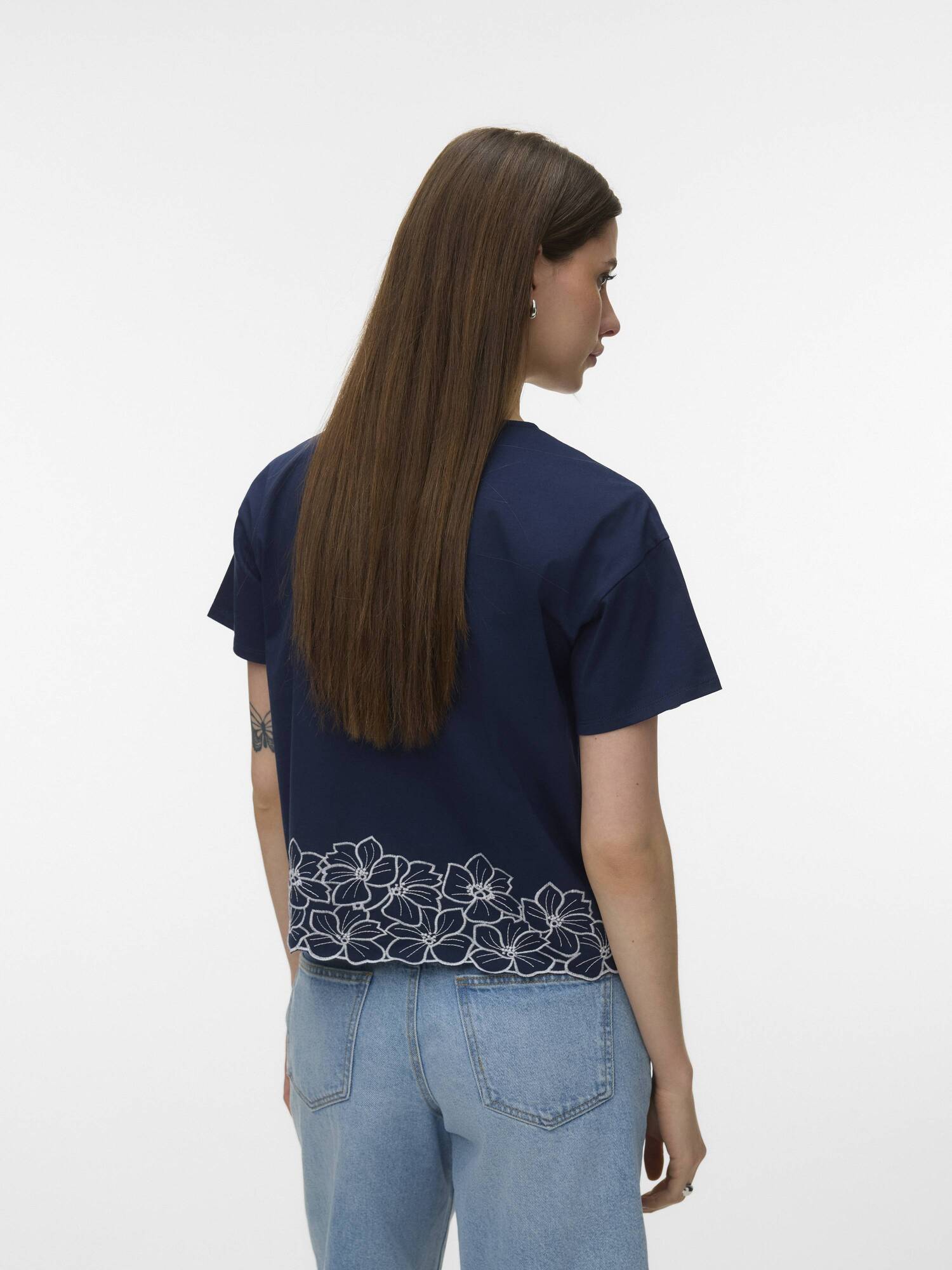 Vero Moda Noah Embroidered Short Sleeve Top in navy with floral embroidery at hem paired with light blue denim jeans