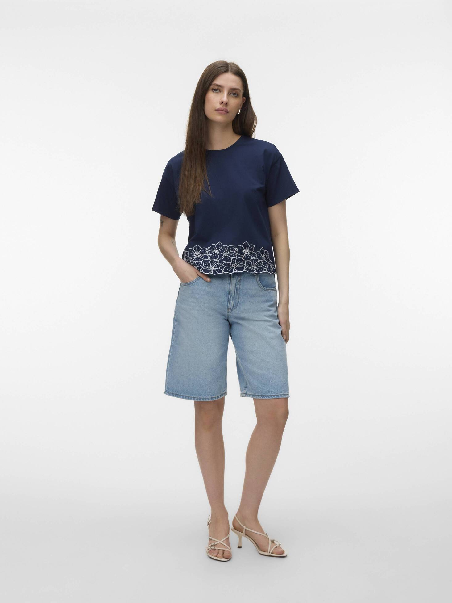 Navy Vero Moda Noah Embroidered Short Sleeve Top with floral hem detail paired with denim shorts and heels