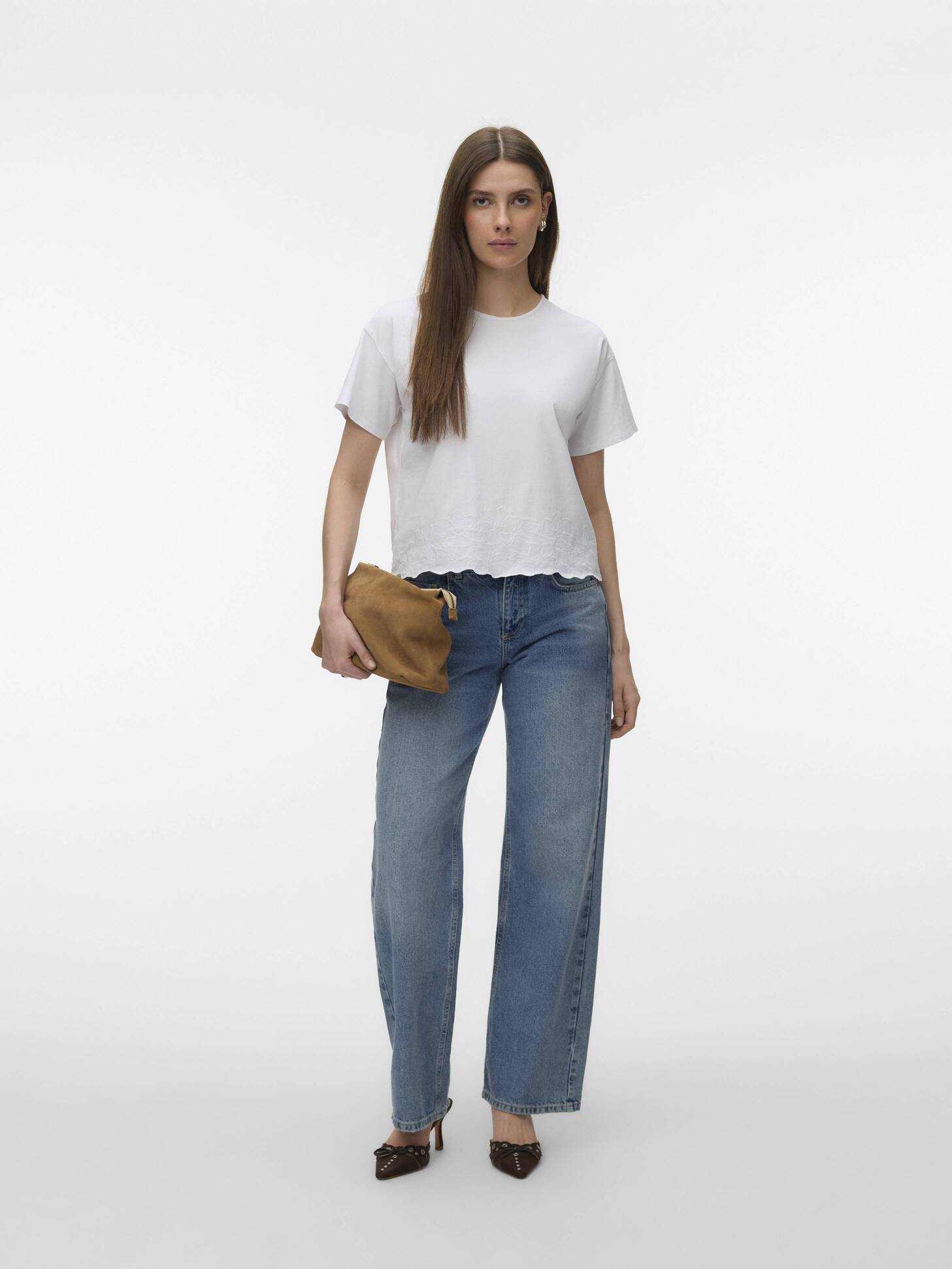 Vero Moda Noah Embroidered Short Sleeve Top in white paired with blue jeans and brown clutch accessory.