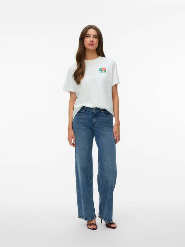 Model in blue jeans and white floral graphic t-shirt, styled with the Vero Moda Maja Flower Bustier Top.