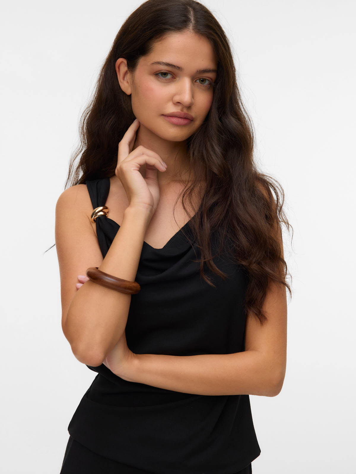 Model showcasing Vero Moda Carly Shoulder Buckle Sleeveless Top in black with wooden and gold-tone bracelets.