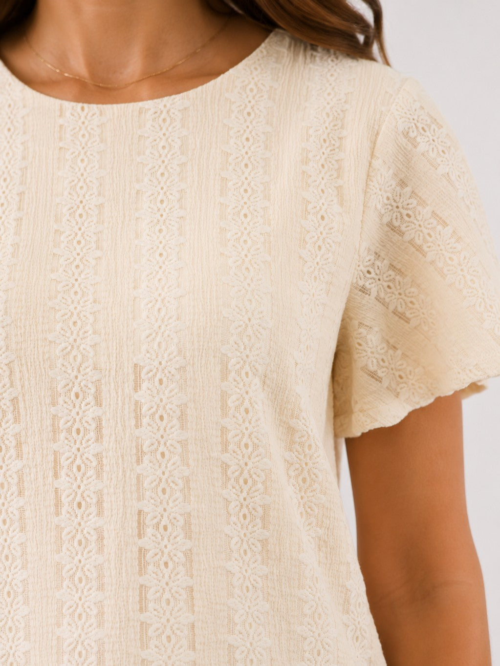 Beige lace textured short sleeve top with a round neckline and intricate vertical patterns.