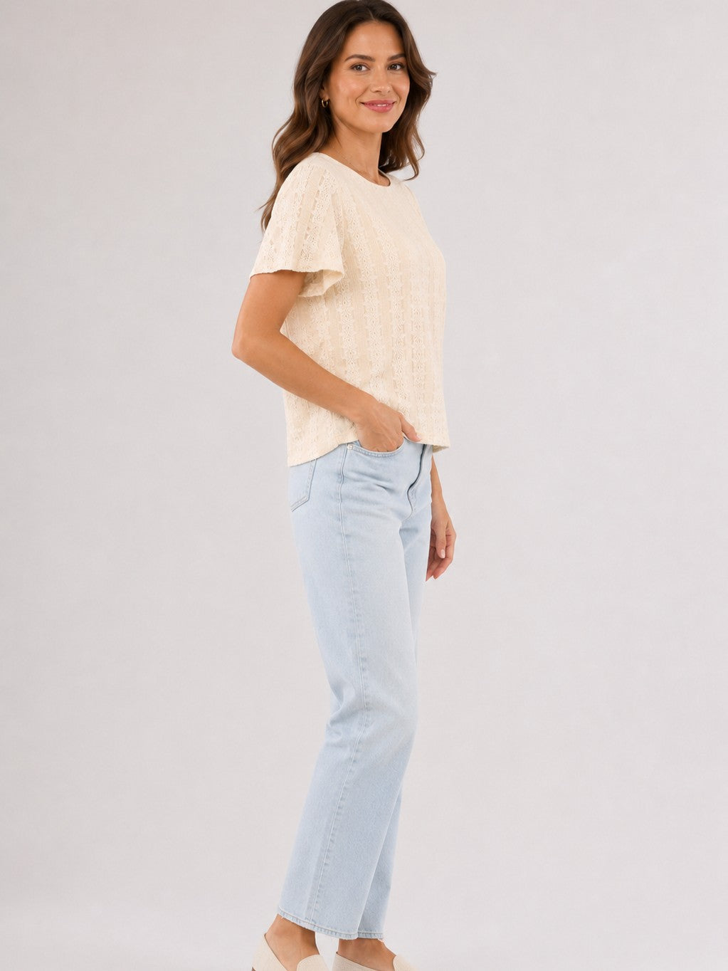 Light beige short-sleeve knit top paired with light blue straight-leg denim jeans on a neutral background.