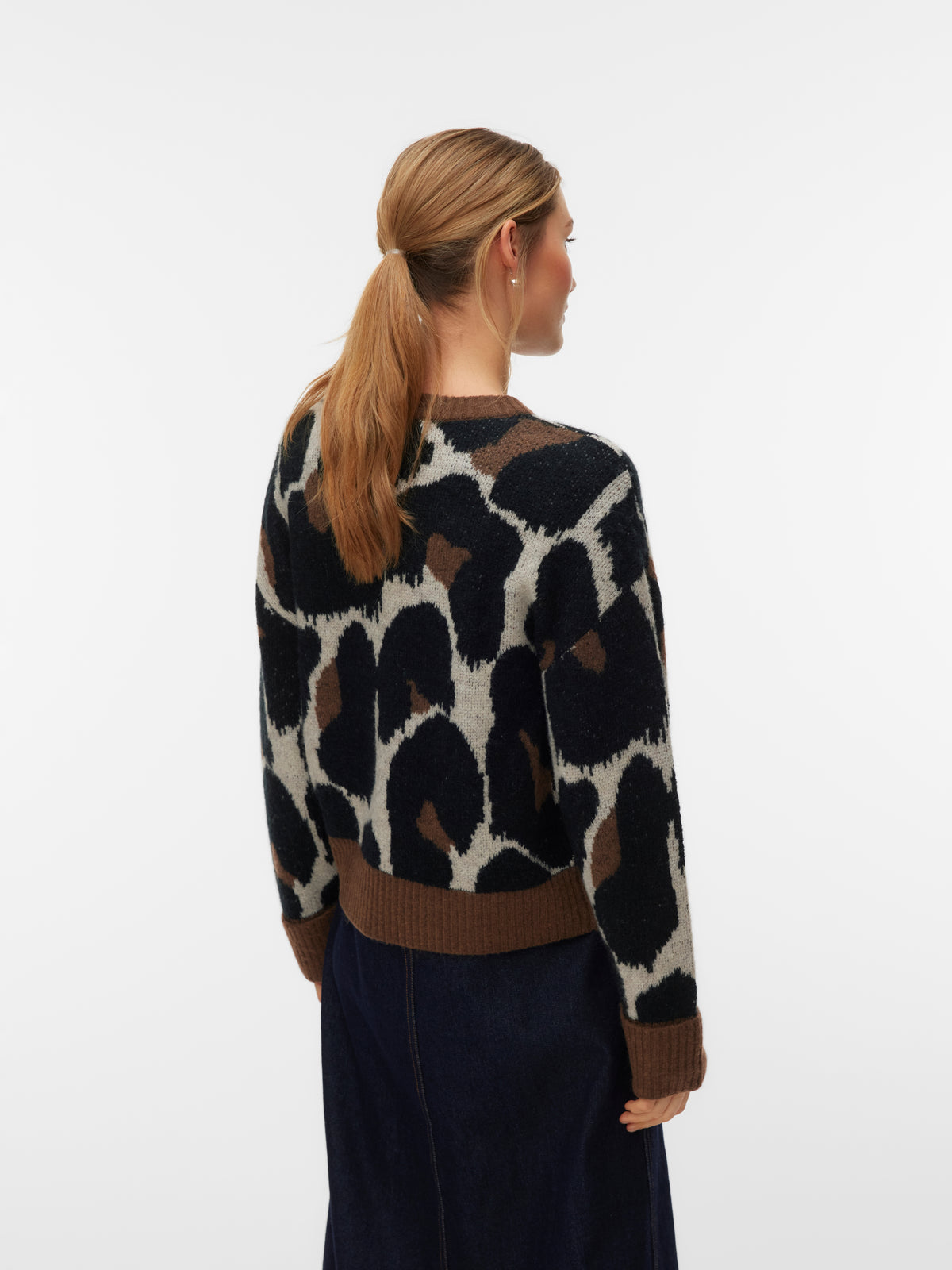 Back view of a crew neck sweater with large abstract animal print in black, brown, and white tones.