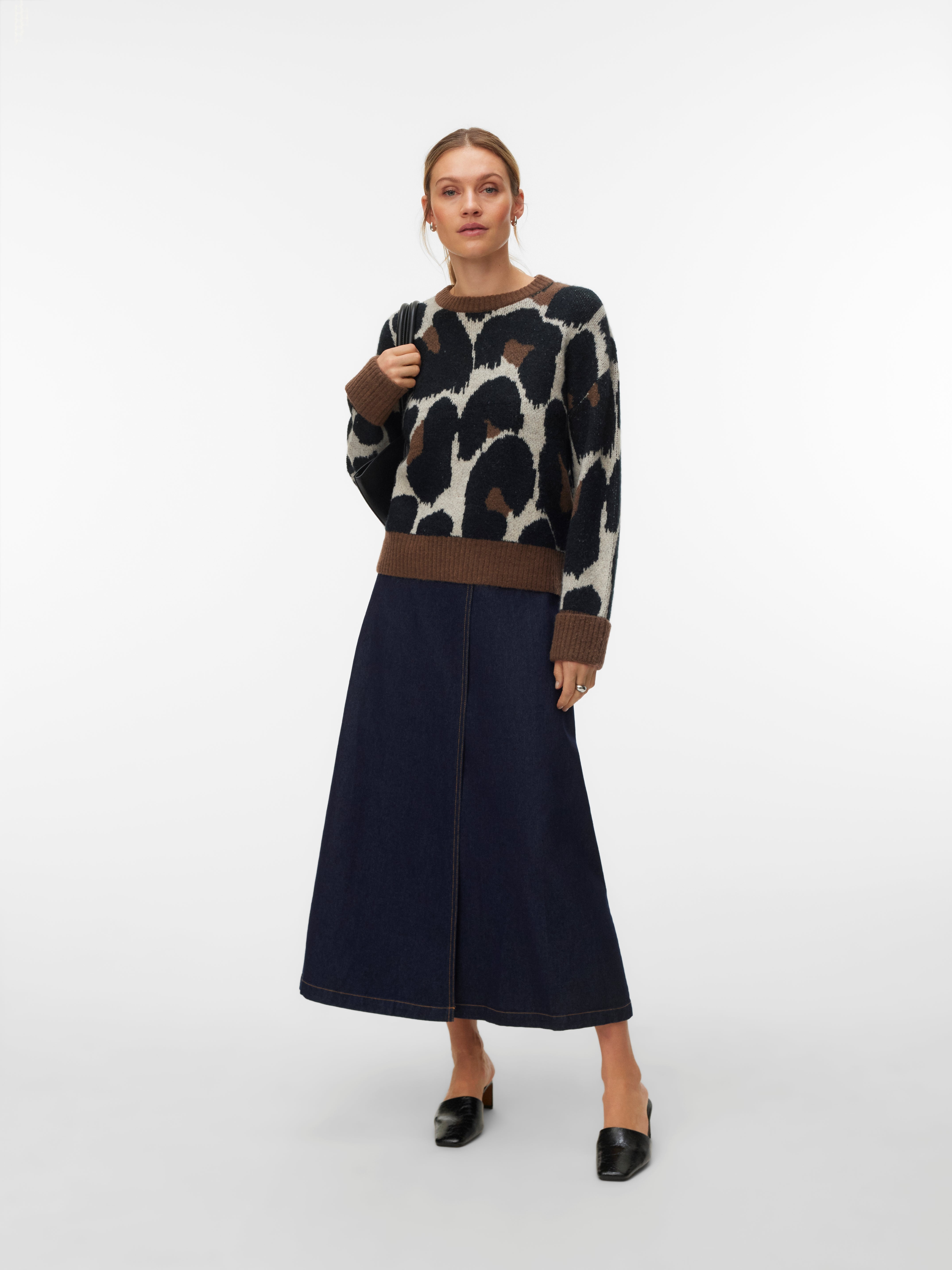 Crew neck sweater with abstract black and brown pattern paired with a long dark denim skirt and black slip-on shoes.