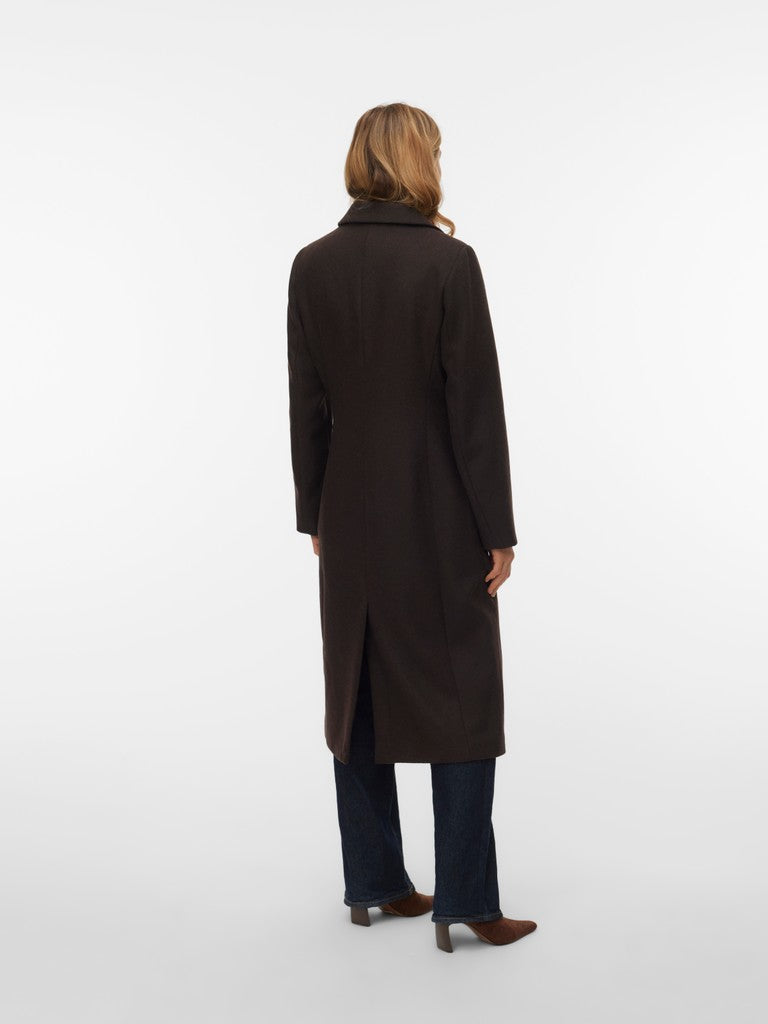Back view of a figure in a long black coat and dark denim jeans against a white background