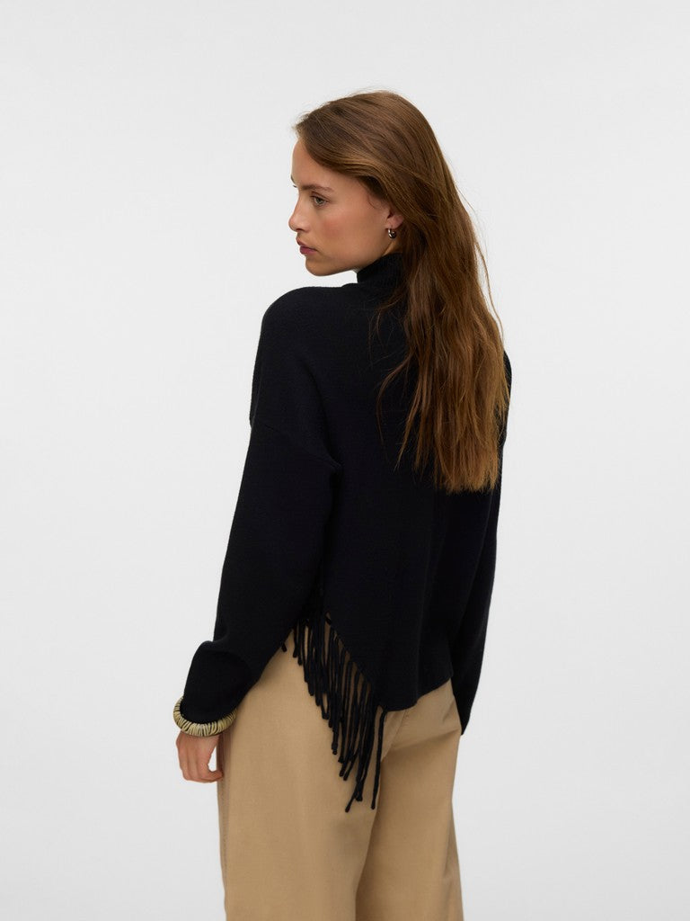Back view of a figure in a black fringed sweater and beige trousers against a white background