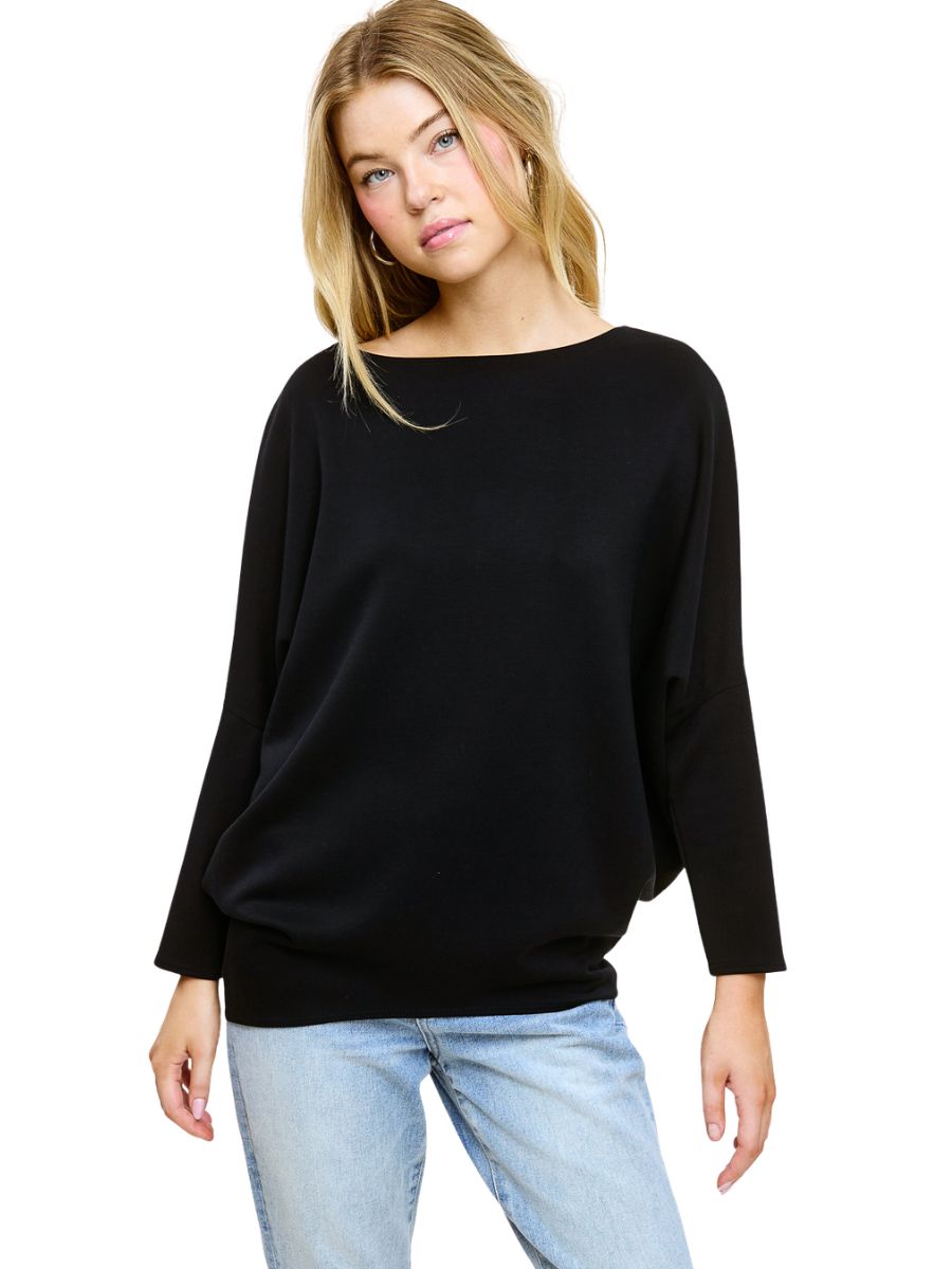 Loose black long-sleeve top paired with light blue denim jeans against a white background