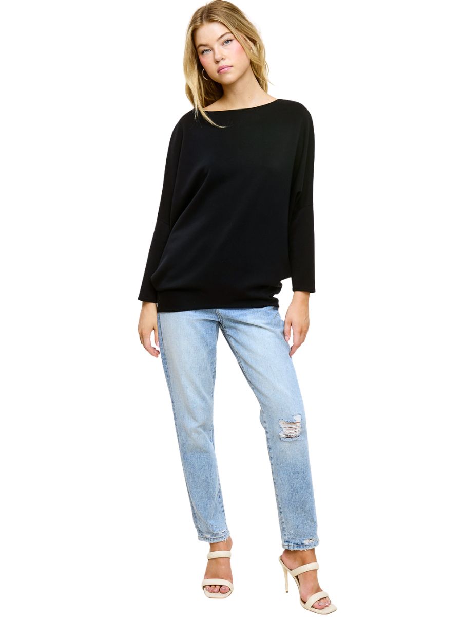 Black long sleeve loose top paired with light blue distressed jeans and beige heeled sandals on white background
